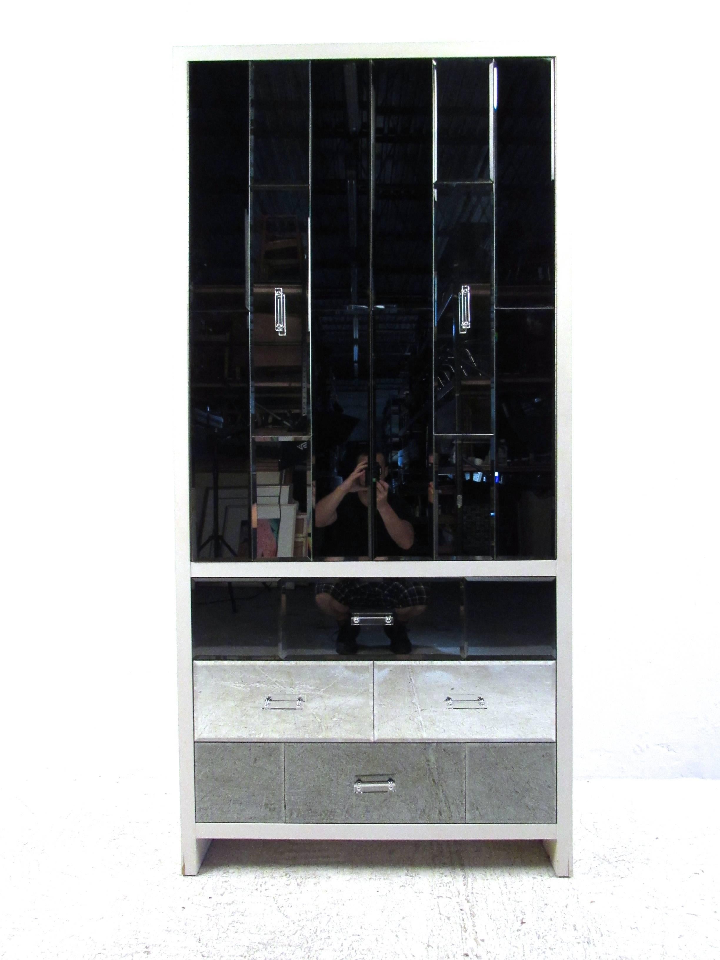 This unique beveled glass armoire features stylish Lucite handles, mirrored finish and plenty of interior storage. Wonderful vintage storage piece for a variety of interiors, this mirror front cabinet makes the perfect addition to any Mid-Century