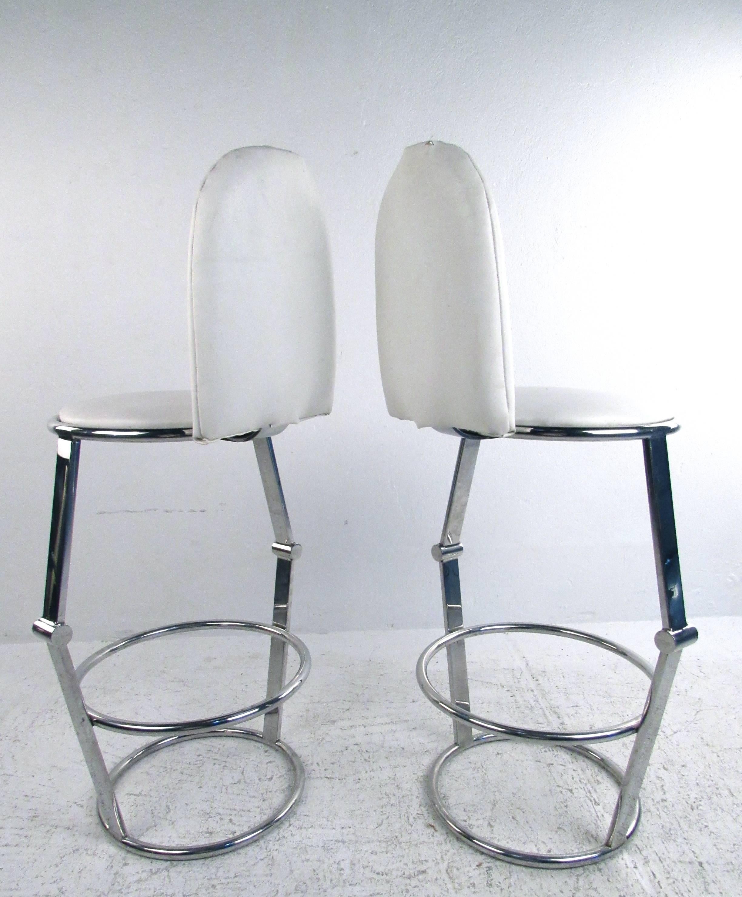 This pair of unique vintage bar stools features a truly unique modern style with comfortable upholstered seats. Chrome frames include circular footrests, with a seat height of 27.5 inches. Please confirm item location (NY or NJ).