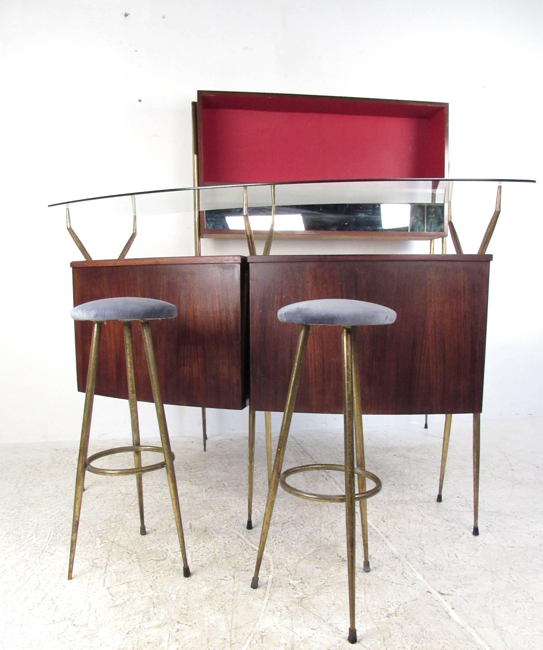 This beautiful modular bar features elegant hardwood construction with vintage brass trim. Pair of matching tripod bar stools perfectly complements the stylish tapered legs of the bar and storage cabinet. Curved glass top and spacious storage behind