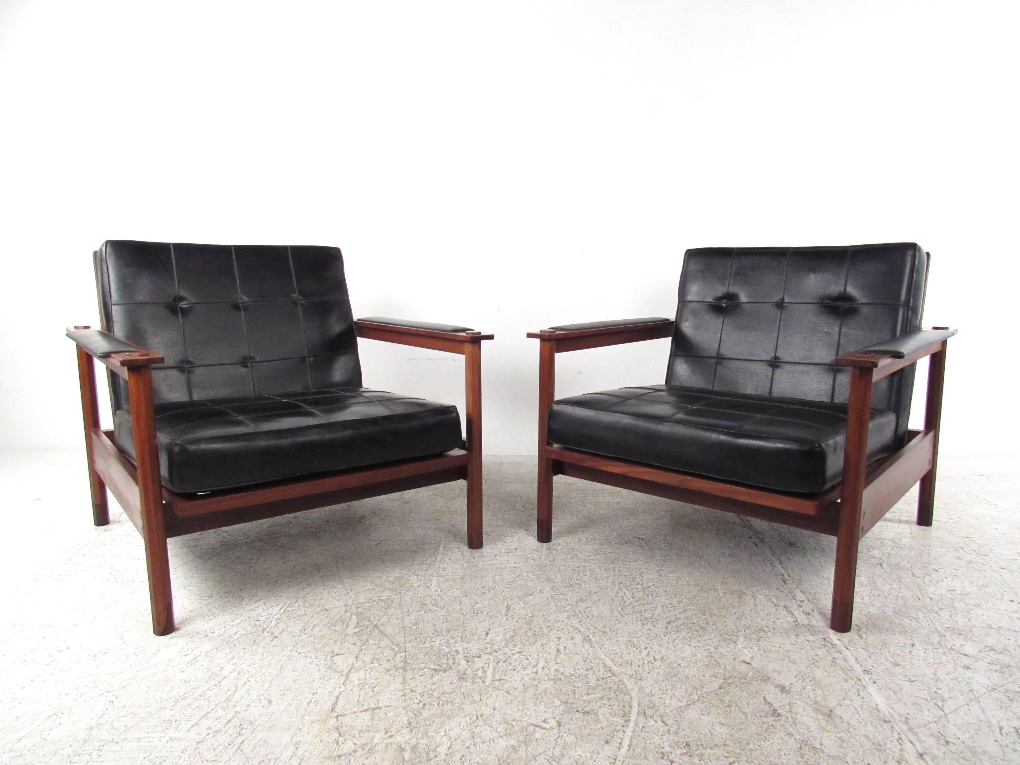 This beautiful pair of walnut and vinyl lounge chairs make a stunning vintage addition to any seating arrangement. Tufted fabric seats also feature multiple seat back angles, vinyl armrests, and octagonal post construction. Comfortable Mid-Century