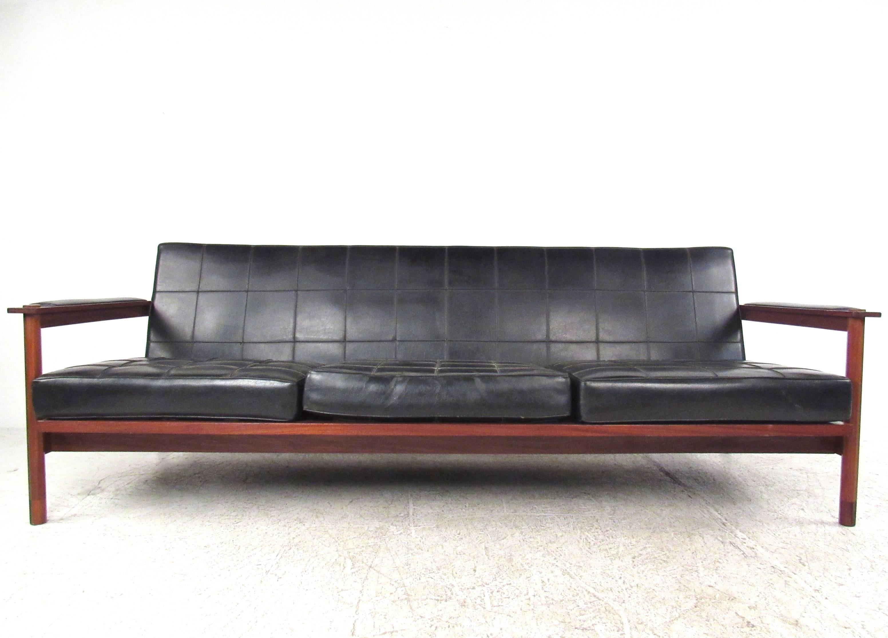 This unique slat back vinyl and walnut sofa features sleek Mid-Century style while making a comfortable addition to any interior. Rich natural finish, tufted vinyl, octagonal post construction, and adjustable seat back set apart this vintage couch.