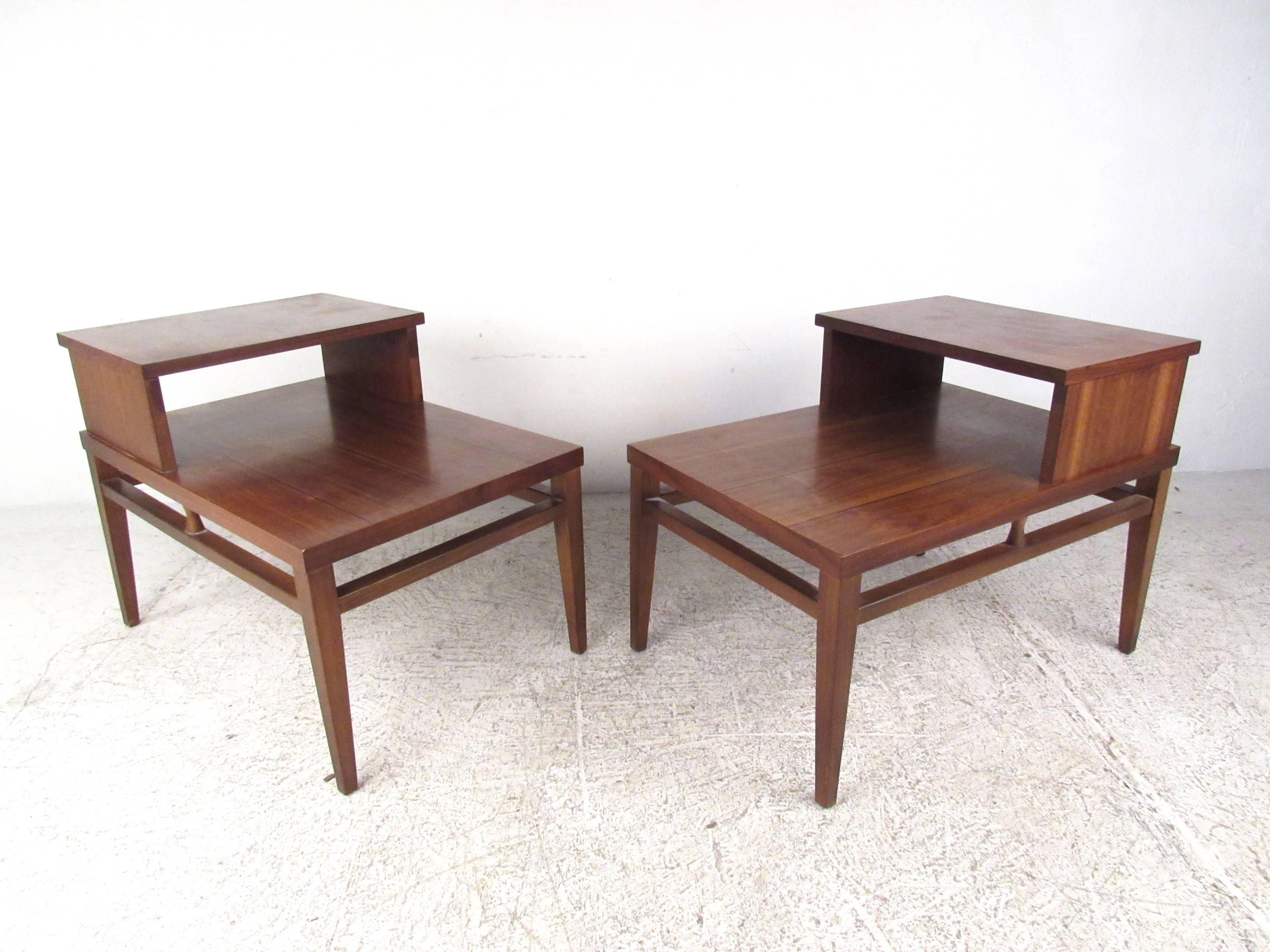 This vintage pair of end tables features stylish Mid-Century design with a beautiful walnut finish. Unique two-tier design with tapered legs and stretchers ensuring sturdiness. This handsome mid-century pair of nightstands work perfectly in any