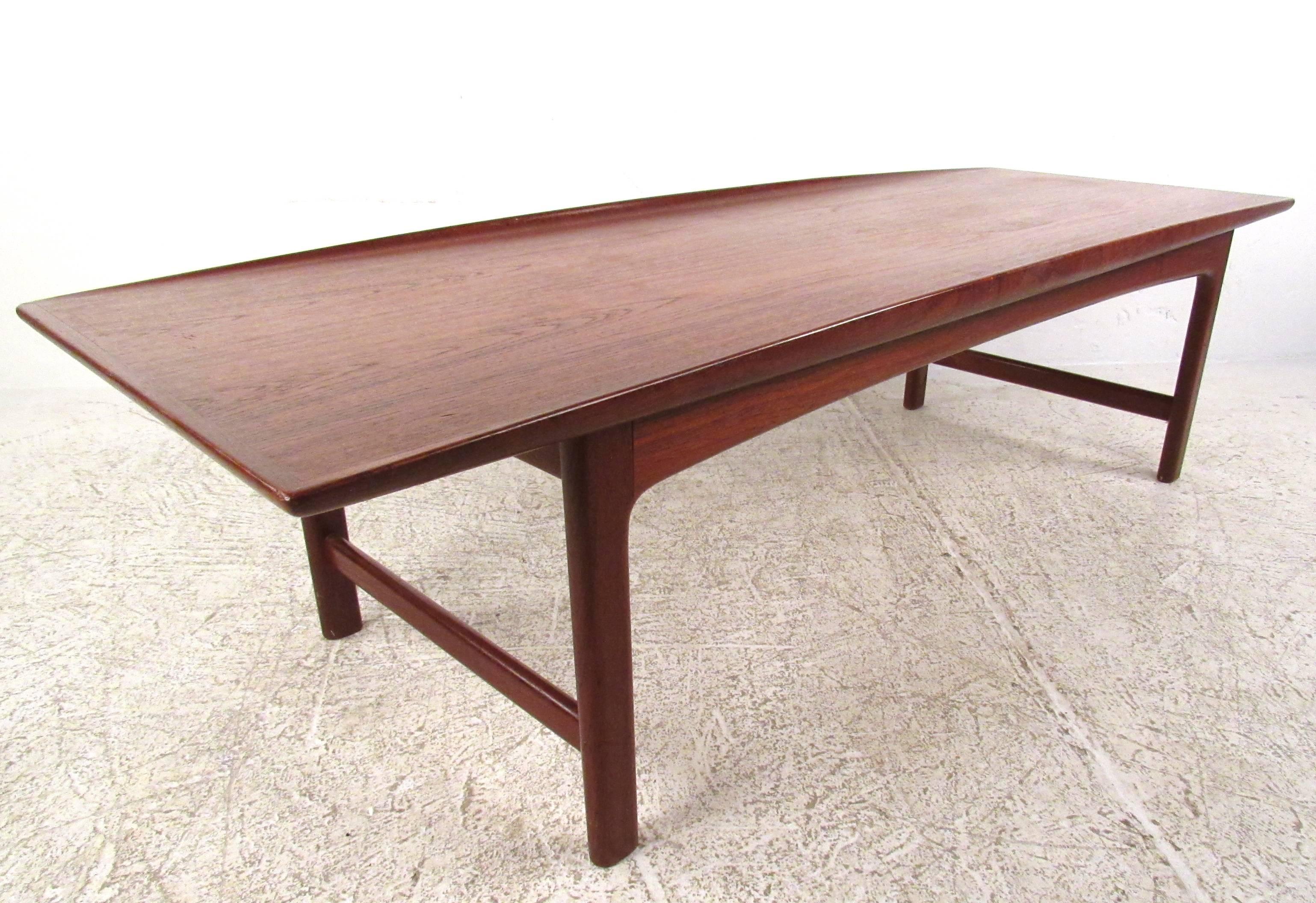 This beautiful turned edge coffee table by DUX is the perfect vintage blend of Danish modern design. Stunning teak finish, shapely design, and stretchers for added stability add to the desirability of this Scandinavian cocktail table. Please confirm