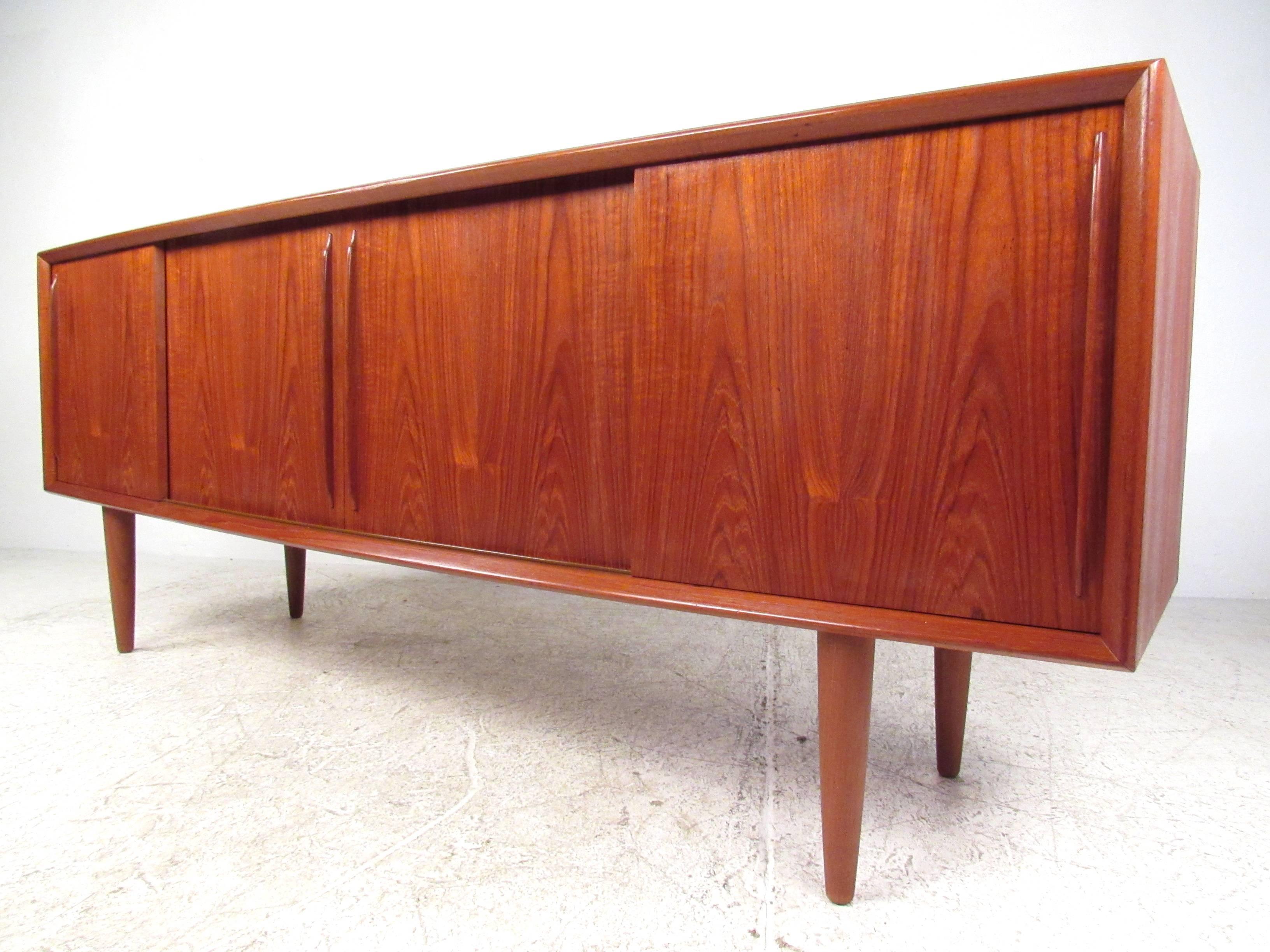 This vintage teak sideboard by HP Hansen combines Mid-Century Modern style with spacious storage options. Sliding doors hide shelves and felt lined drawers and feature elegantly carved wood handles. Original HP Hansen manufacturer's mark on back,