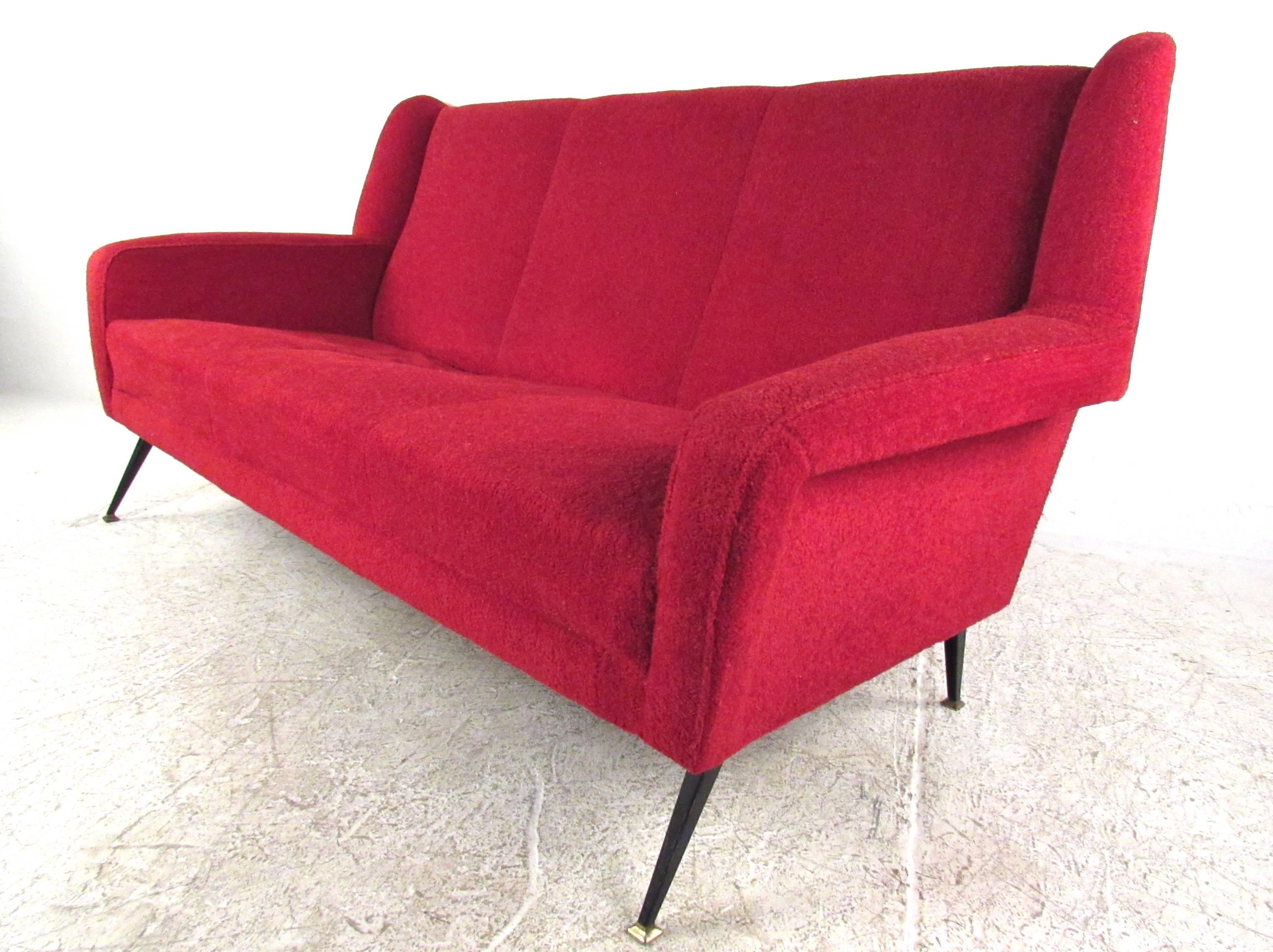 This vintage Italian sofa features the unique Mid-Century design style of Marco Zanuso. Sculpted upholstered frame makes for a comfortable seating option while enhancing the modern style of the piece. Black metal legs have brass finish feet. Unique