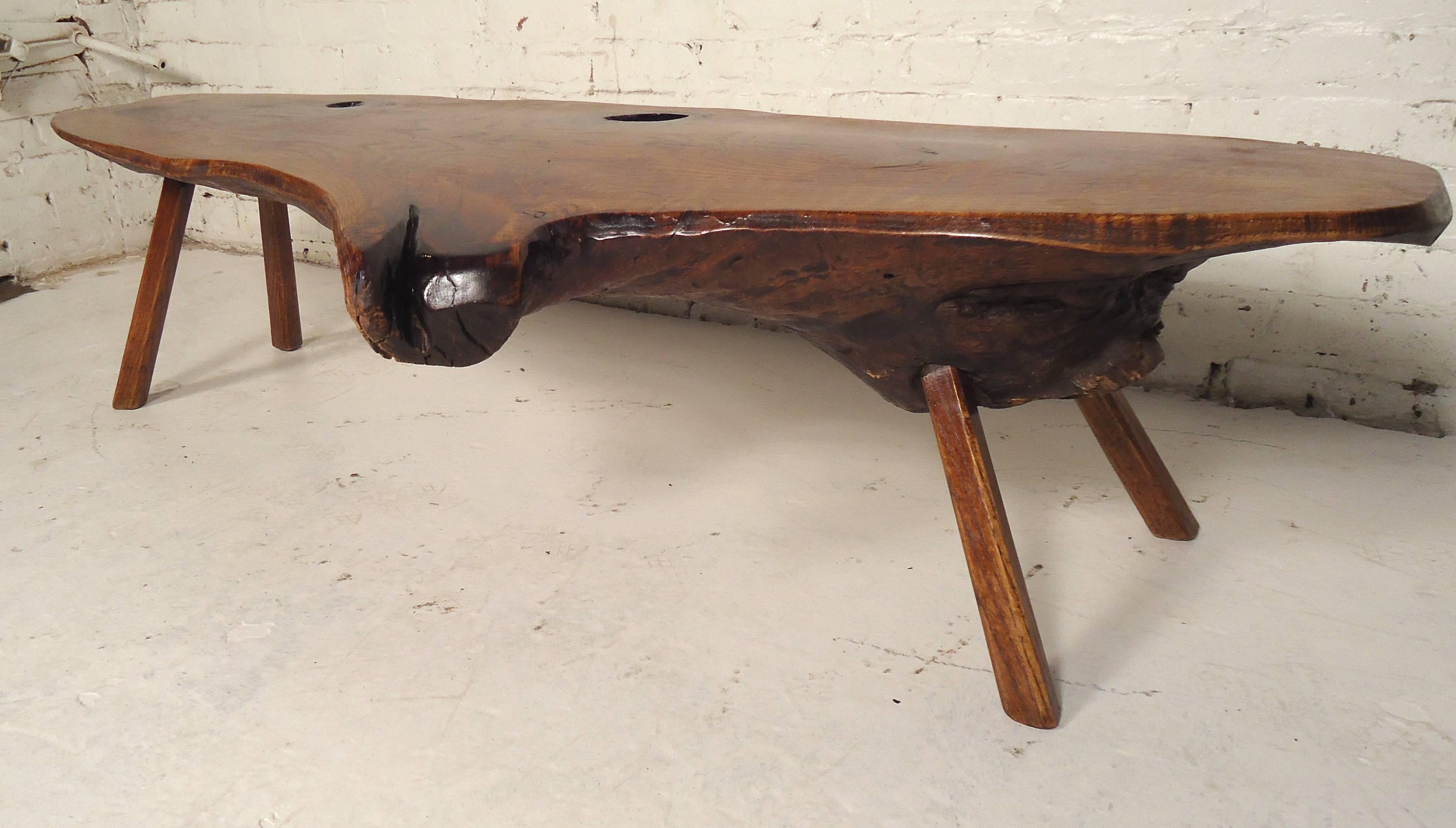 This vintage live edge coffee table features a thick tree slab top mounted on splayed legs. This large and uniquely shaped coffee table is a visually impressive addition to a variety of interiors. 

Please confirm item location (NY or NJ).