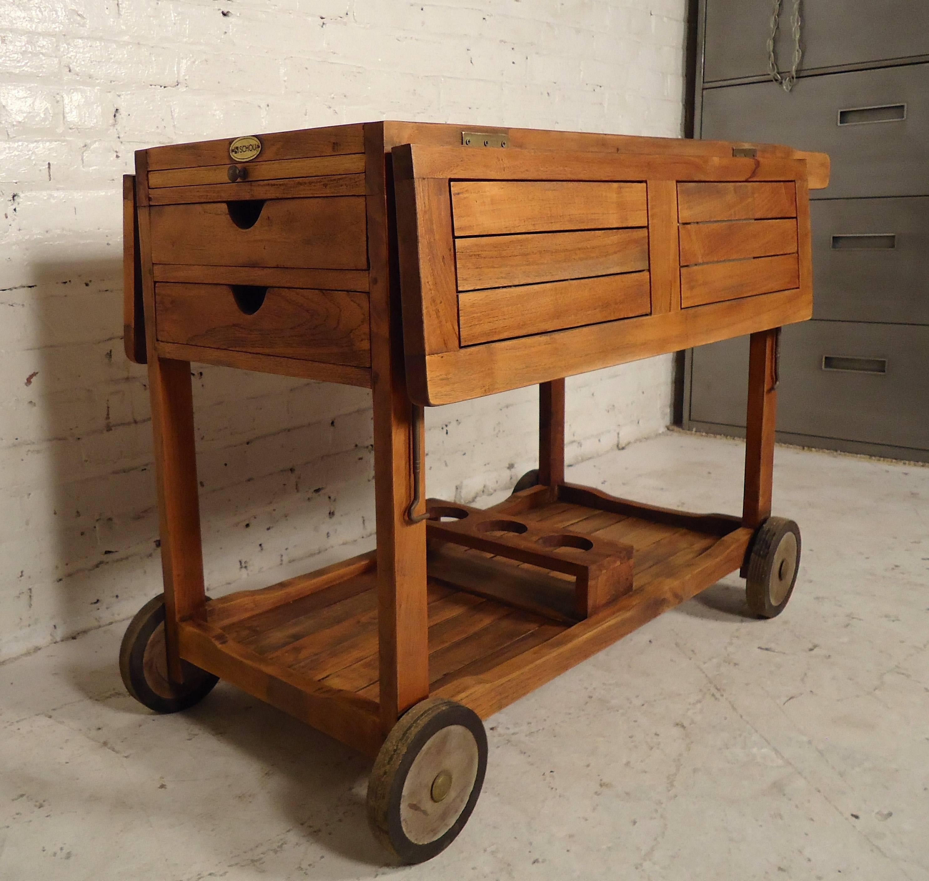 Rustic vintage-modern serving cart featuring two extending drop leafs, two small drawers for storage use, a cutting board, and bottle holders at the bottom tier. This cart is on a set of four wheels making it easy to maneuver.
Each leaf: 9.5