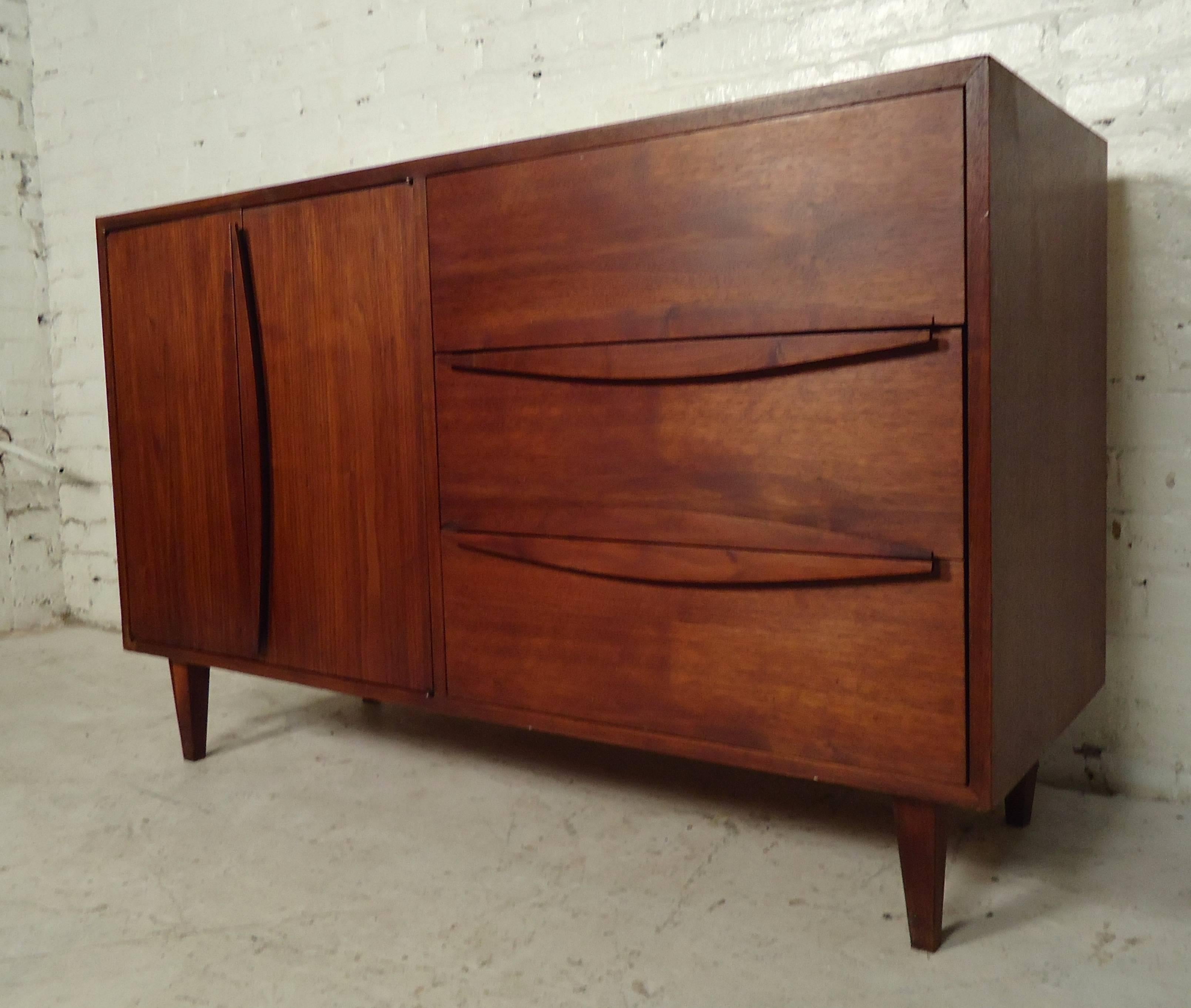 Stunning vintage-modern cabinet with rich teakwood grain, dual door cabinet storage, and three pull drawers with uniquely sculpted handles.

Please confirm item location NY or NJ with dealer.
