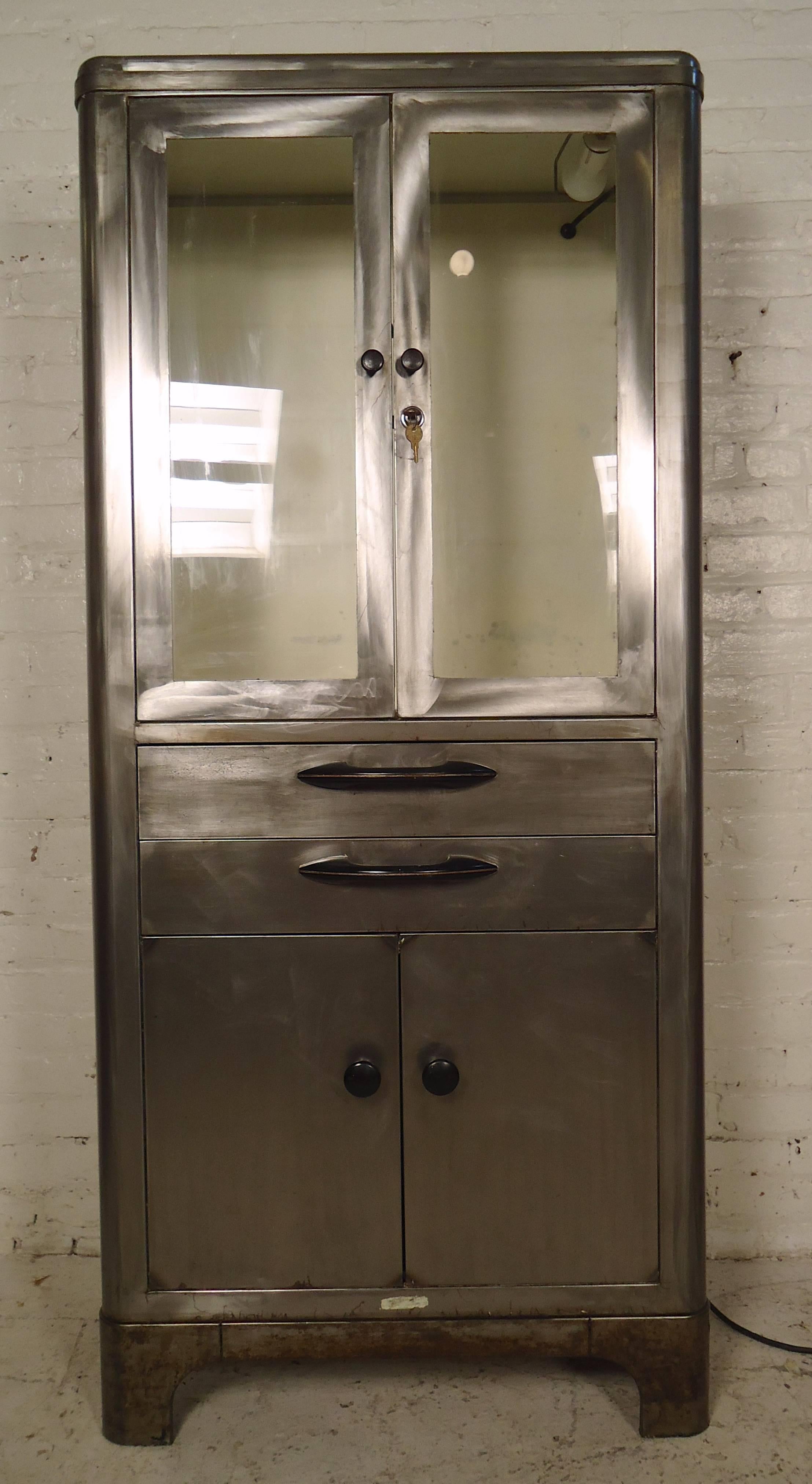 Heavy duty metal storage cabinet restored in a unique Industrial style finish. Features glass cabinet with working light, middle drawers and bottom cabinet. Top cabinet has locking key on the right door and locking bar on the left. Shelf clips are