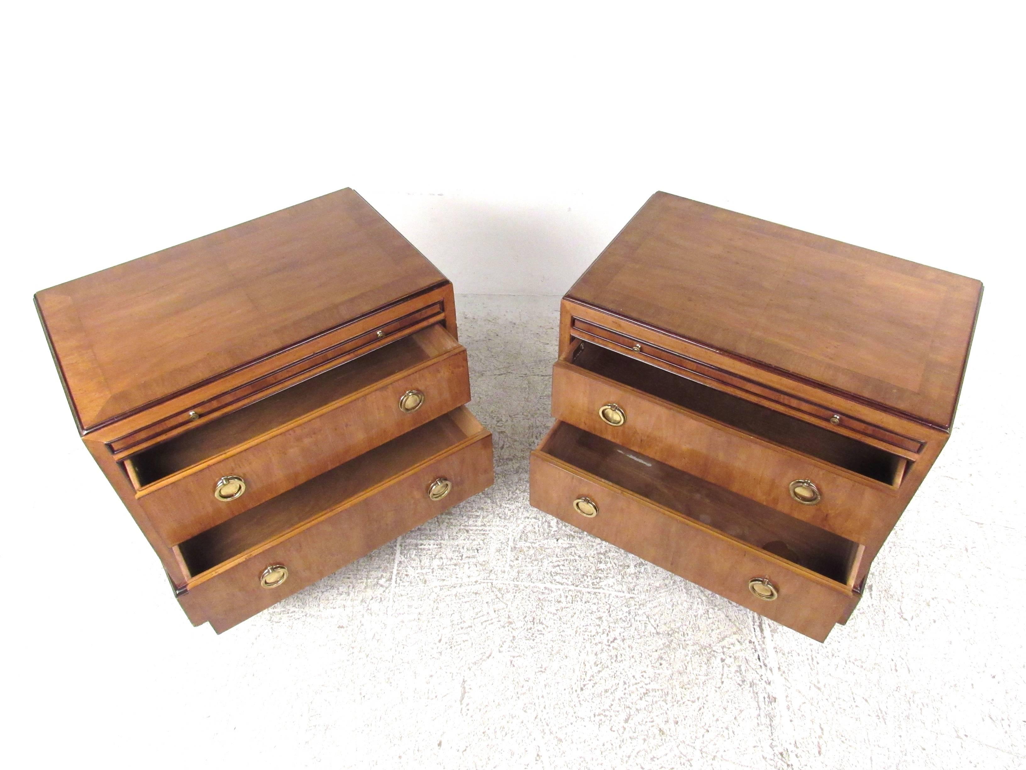 This stunning pair of Mid-Century nightstands features brass ring pulls and a remarkable vintage finish. Plenty of storage in these two-drawer matching end tables, complete with pull-out tray. Unique trim and shapely design make these a stylish