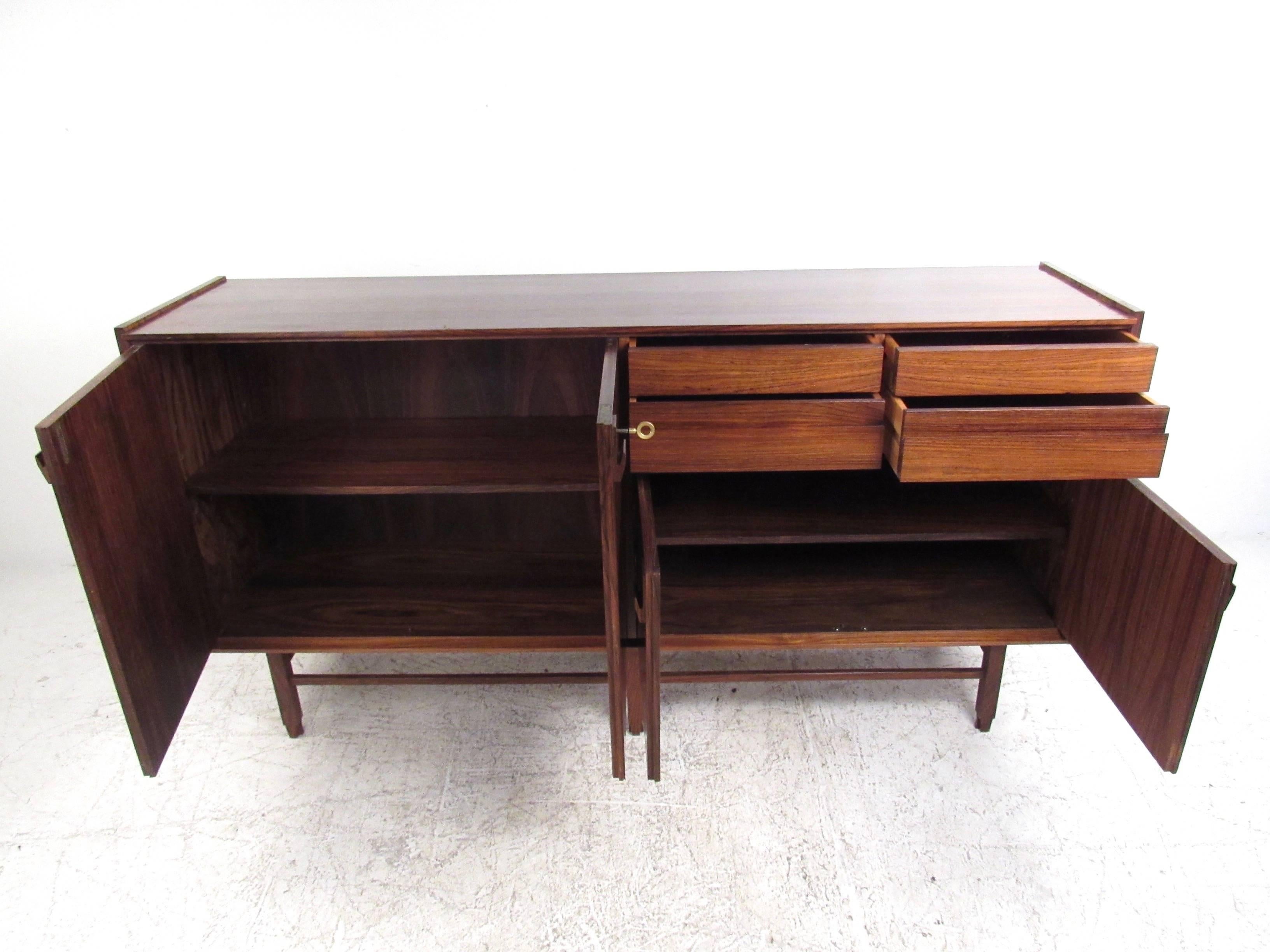 This stunning vintage sideboard features a beautiful rosewood finish with a unique assortment of storage options. Mixed use with drawers and cabinets make this a versatile addition to any room, and an excellent server, sideboard, or television