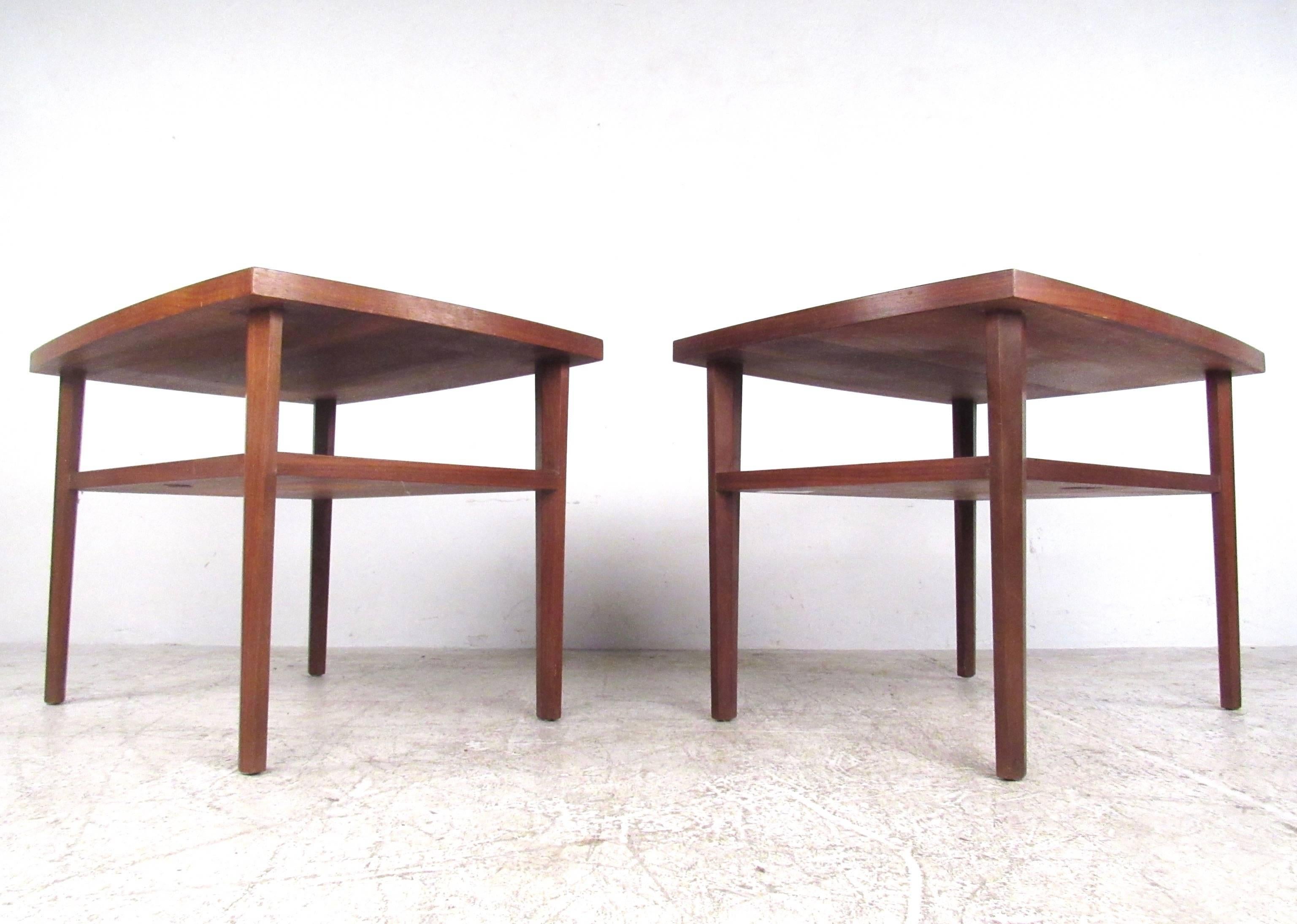 The stunning simplicity of this beautiful vintage pair of tables lies in their subtle shape, sundra finish and high quality walnut construction. Sculpted legs, a two-tier design and original manufacturer's label showcase the impressive Mid-Century