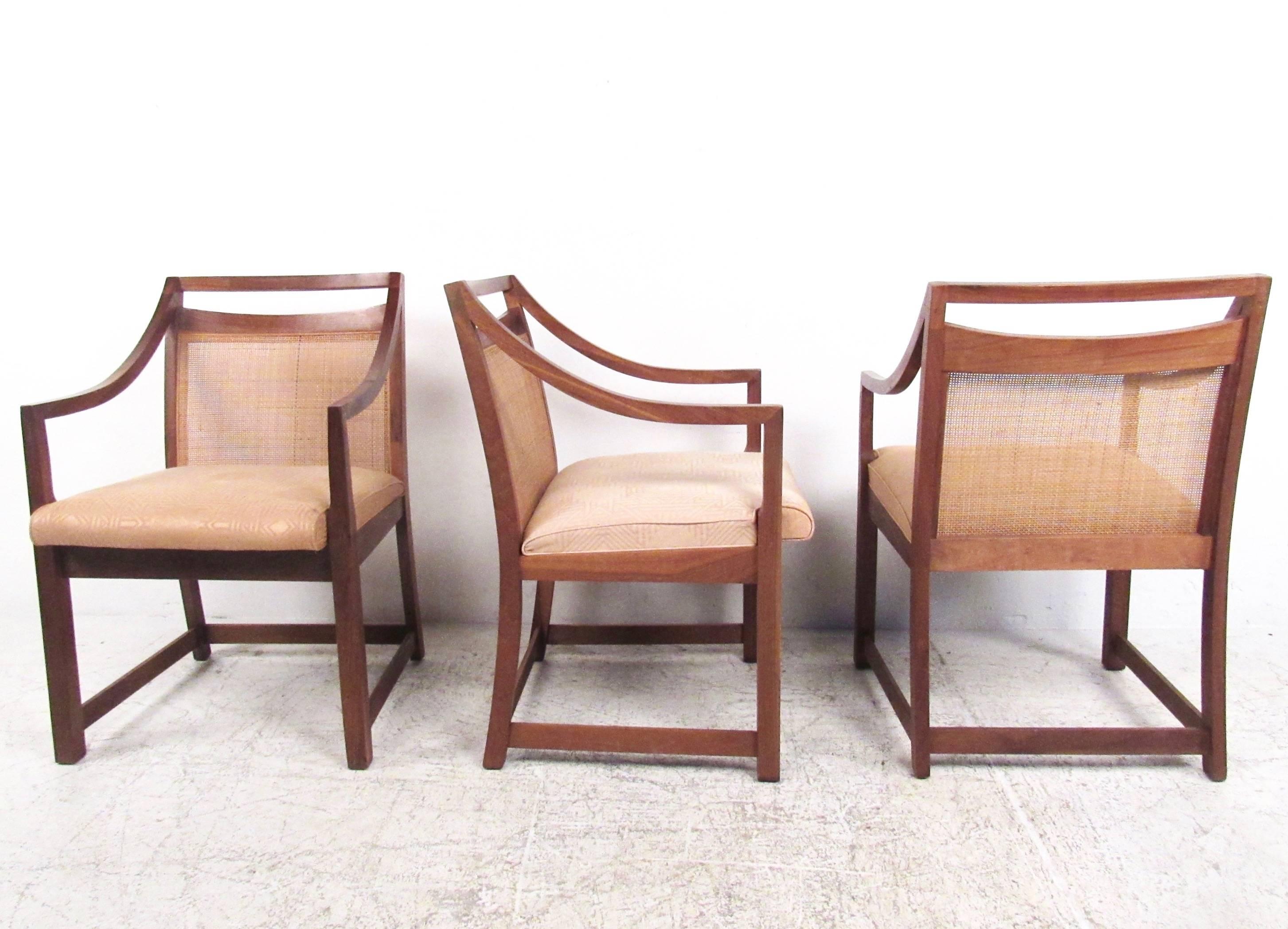 This set of eight vintage dining chairs features quality construction and unique cane seat backs. Sloped armrests accentuate the style of the set, while upholstered seats ensure comfort in any situation. Please confirm item location (NY or NJ).