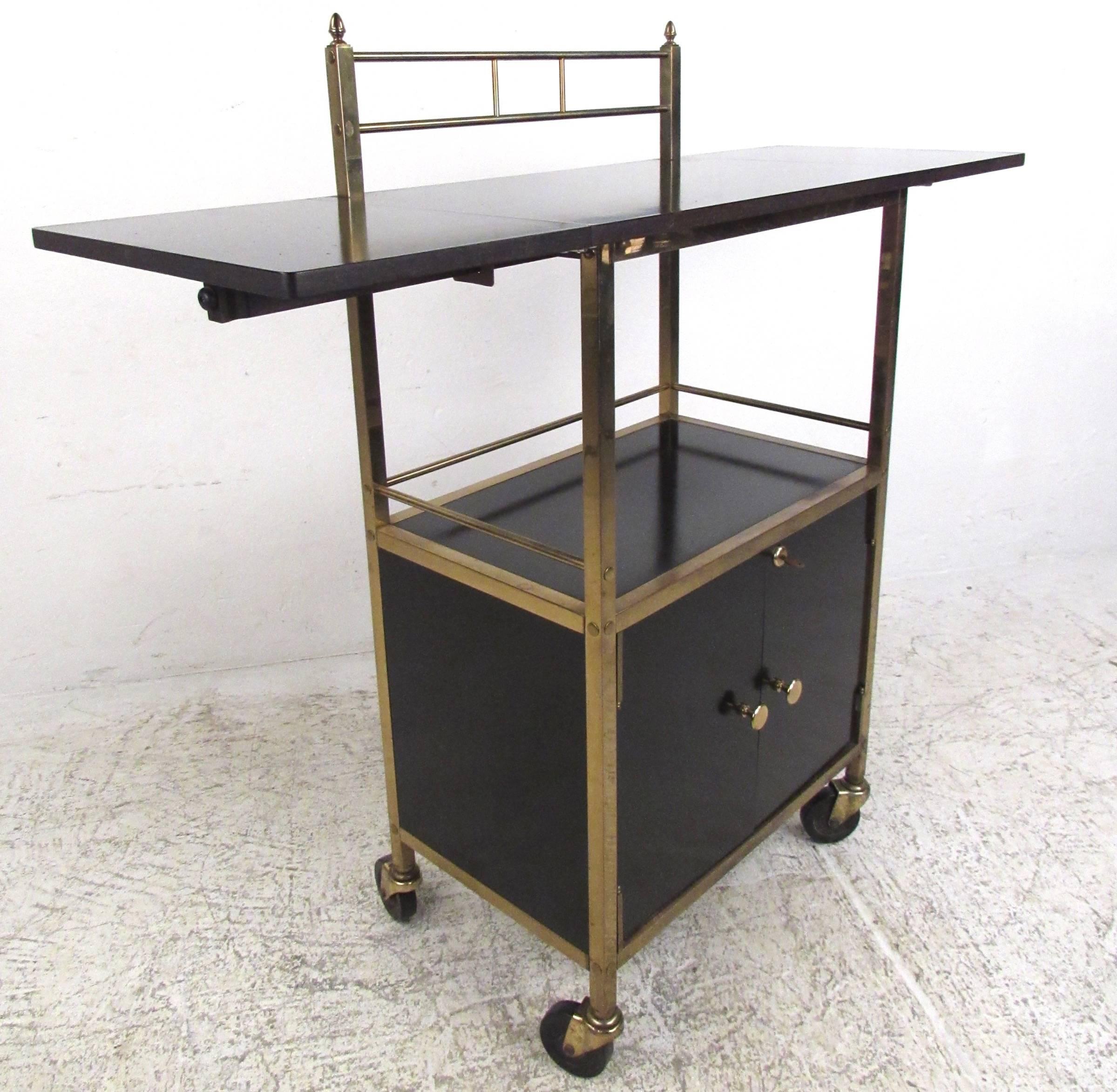 This unique vintage serving cart features a beautiful mix of black lacquered metal and brass details. Collapsible table top makes this service cart a versatile addition to any setting. Locking cabinet storage for liquor and plenty of shelf space for