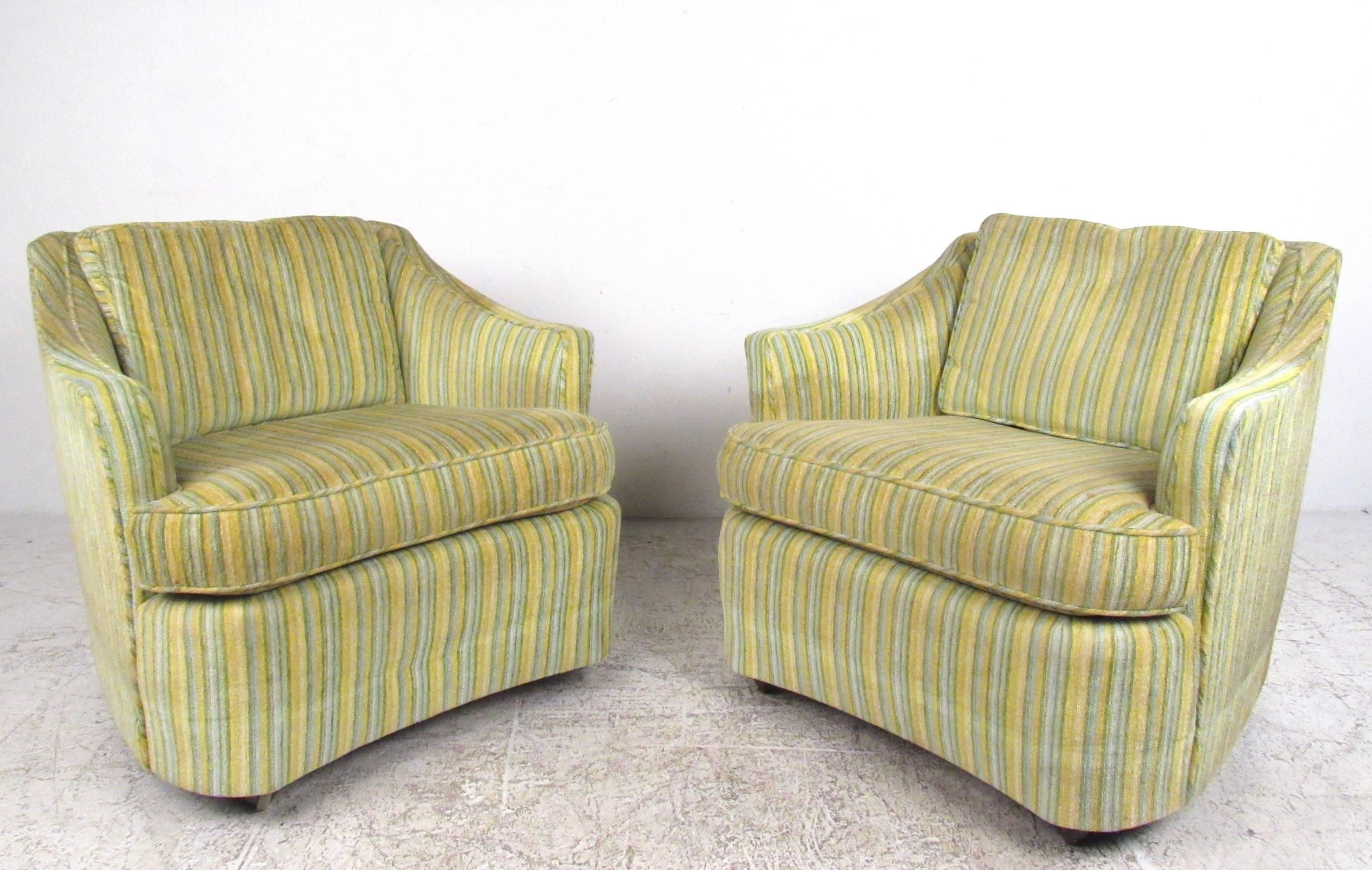 This pair of vintage club chairs features comfortably upholstered frames, with wide seats and sloping armrests. Manufactured in High Point, North Carolina this matching Mid-Century set was produced by Heritage Distinguished Furniture and features an