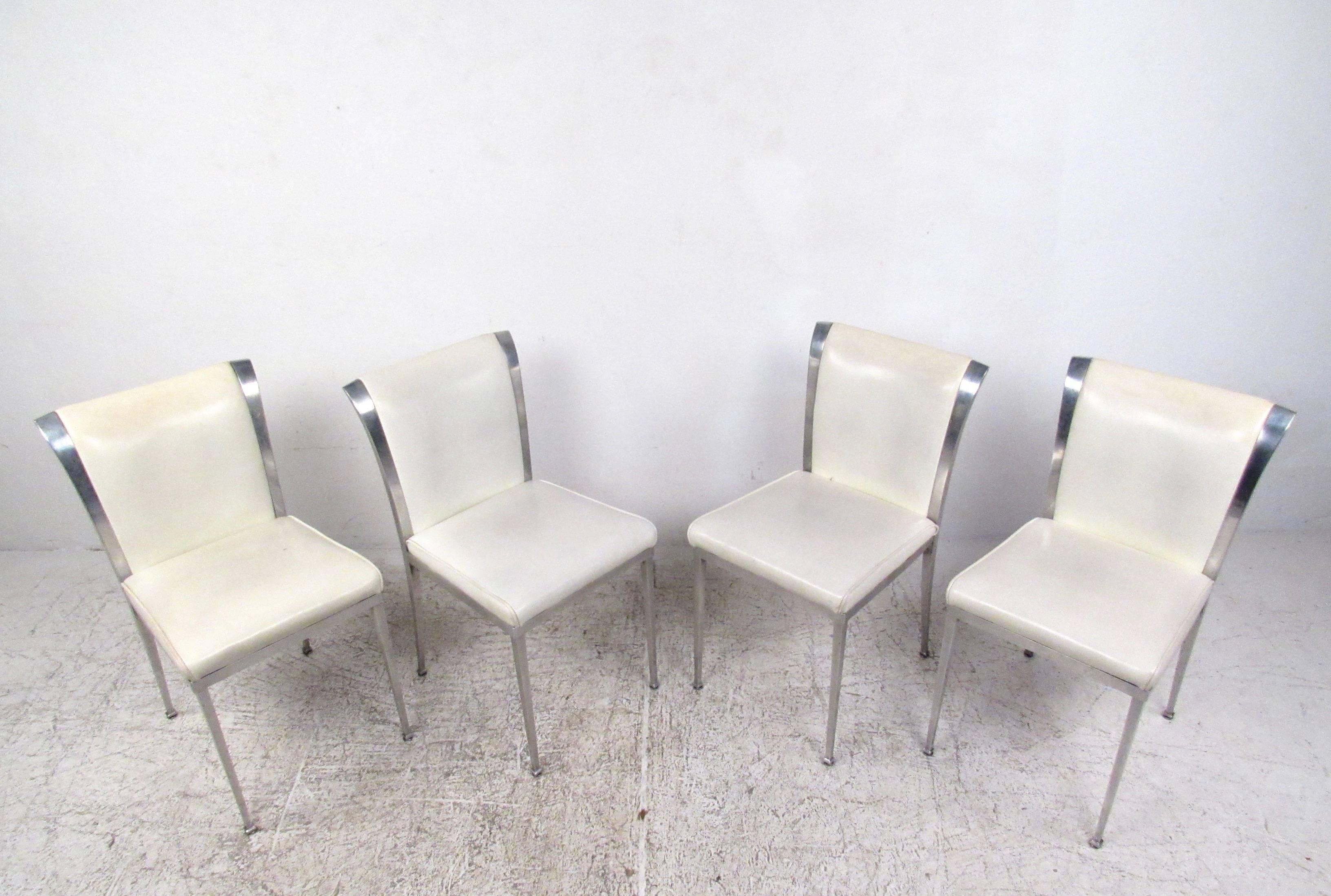 Dieses Set aus vier Vintage-Esszimmerstühlen besteht aus robusten Aluminiumrahmen mit einteiligen Füßen und konischen Rückenlehnen. Die leicht ausgestellten Rückenlehnen sind mit Vintage-Vinyl gepolstert und unterstreichen die moderne Ausstrahlung