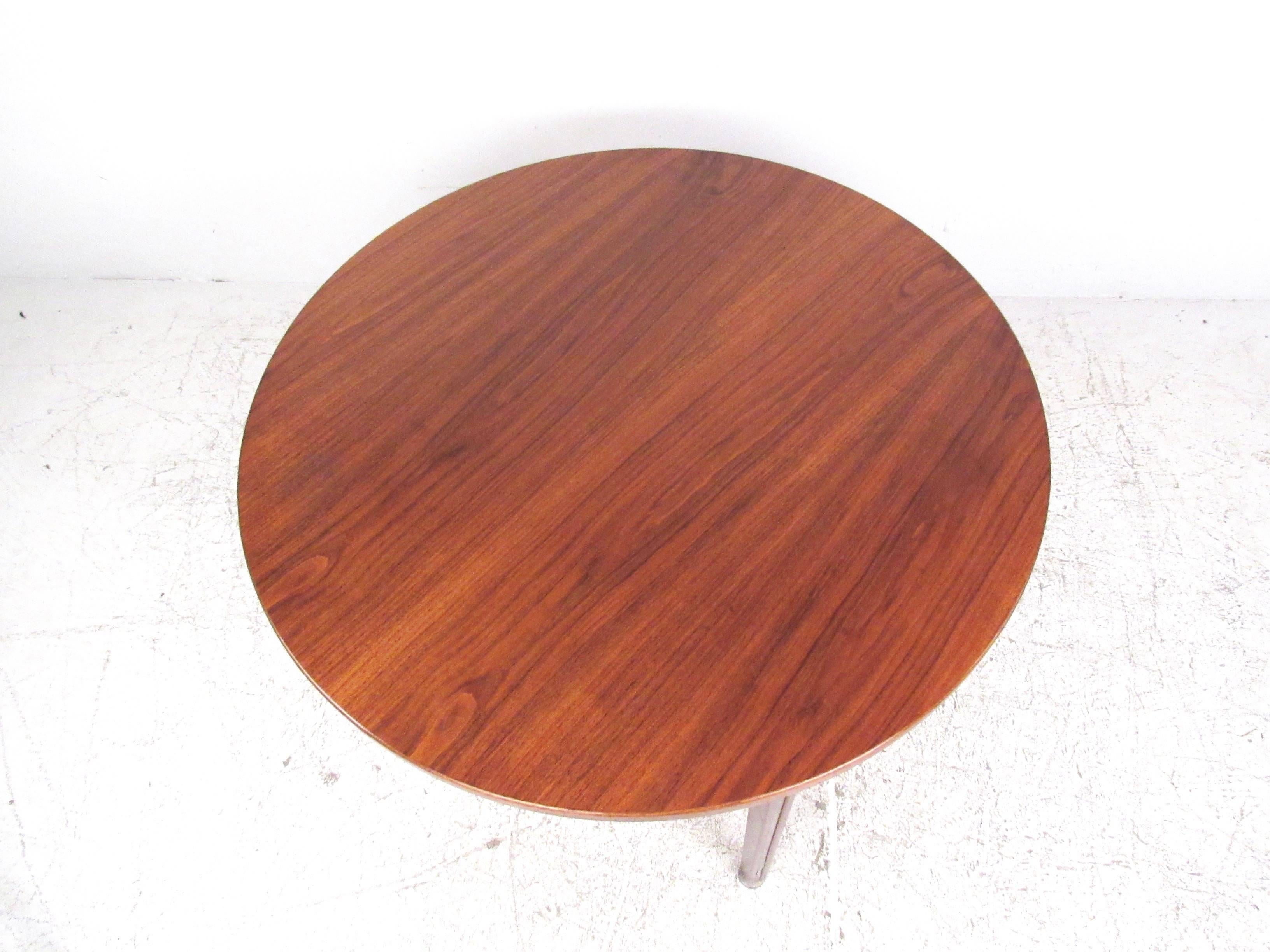 This stunning Jens Risom design dining table is constructed from beautiful Mid-Century teak. Iconic yet practical Danish design makes this a stunning table perfect for home or business use. Three leg design is complimented by aluminum trim and rich
