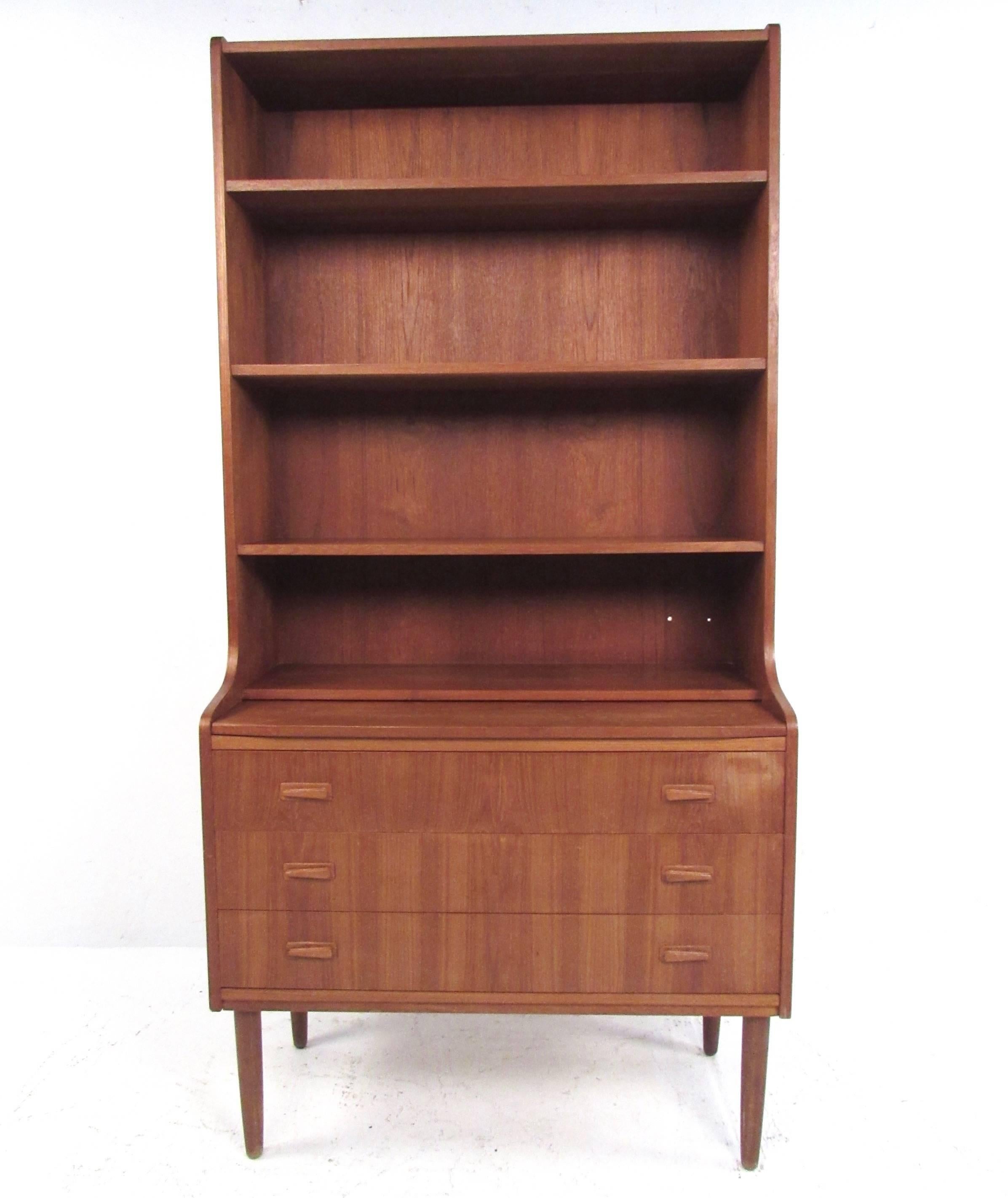 This stunning vintage modern secretary combines Mid-Century Danish style with space saving versatility. Four shelves for storage and display are complimented by three spacious drawers with unique carved drawer pulls. Pull-out writing table provides