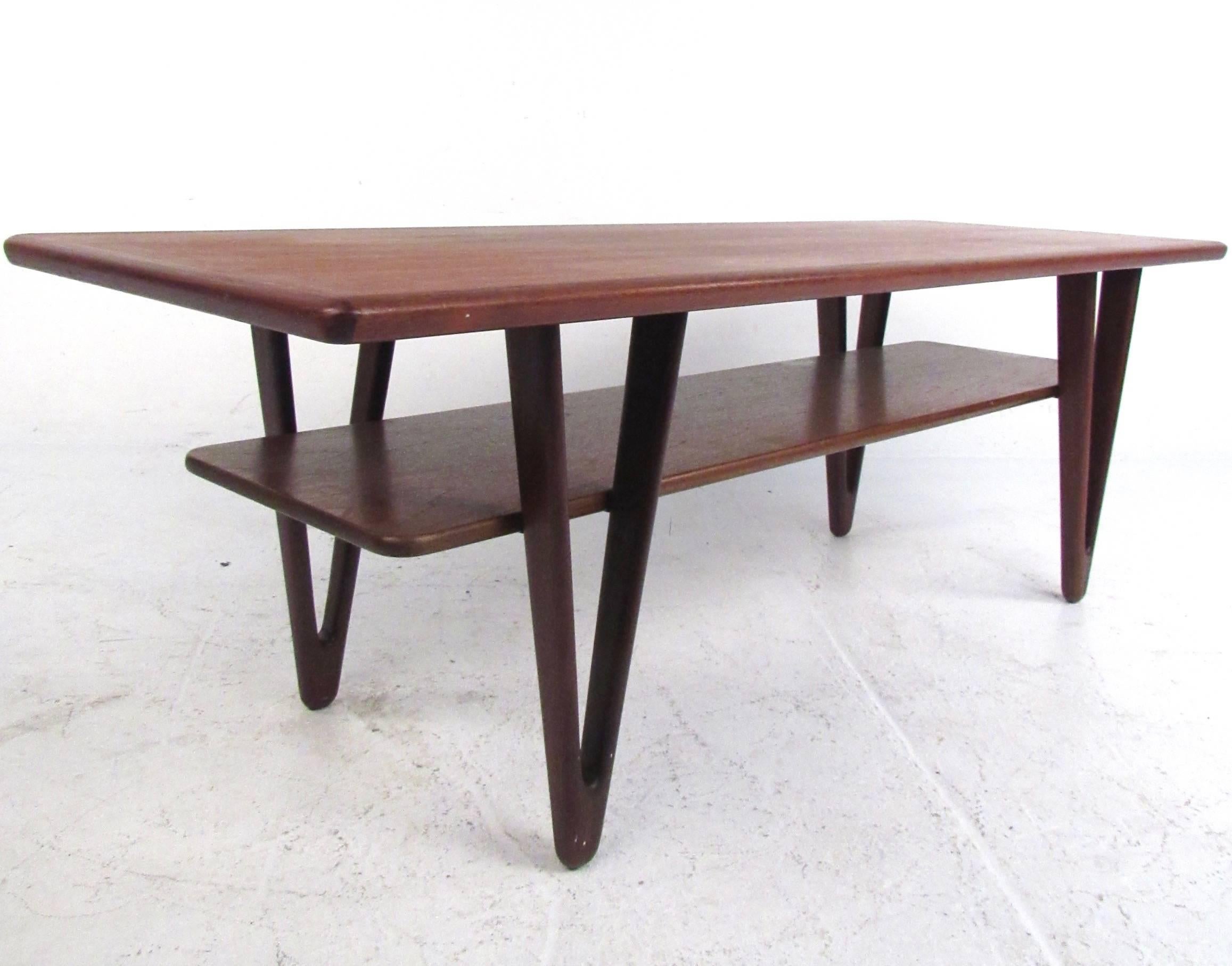 This stunning vintage modern coffee table by Kurt Ostervig features unique sculpted legs and a second tier shelf for extra storage. Visually impressive design sets this unique triangular leg table apart from other Mid-Century options, and makes this