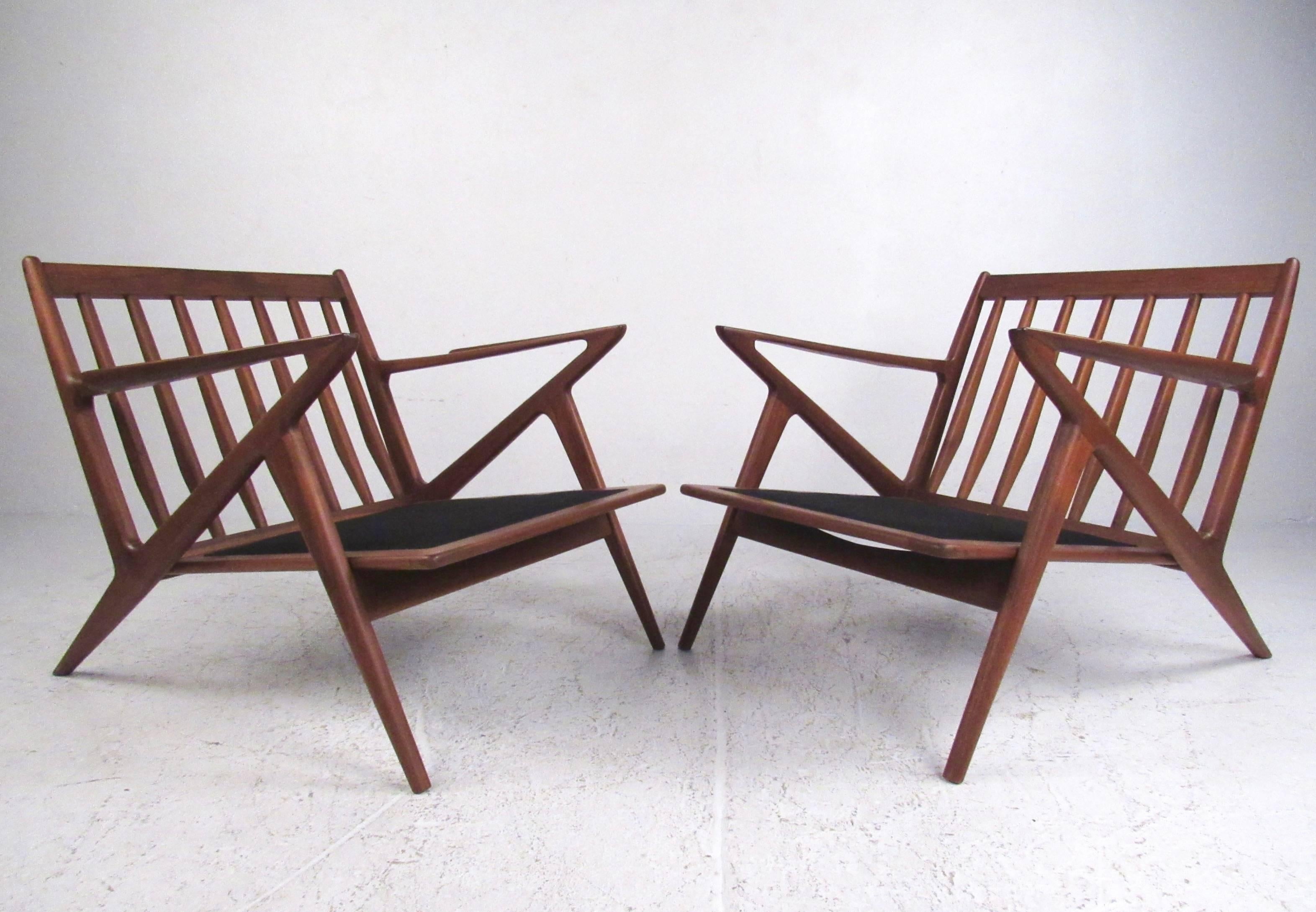 This exquisite Mid-Century style pair of teak lounge chairs feature stunning sculpted frames with slat backs and unique angles. Excellent addition to any modern interior, this beautiful pair combine impressive design with timeless comfort. Please