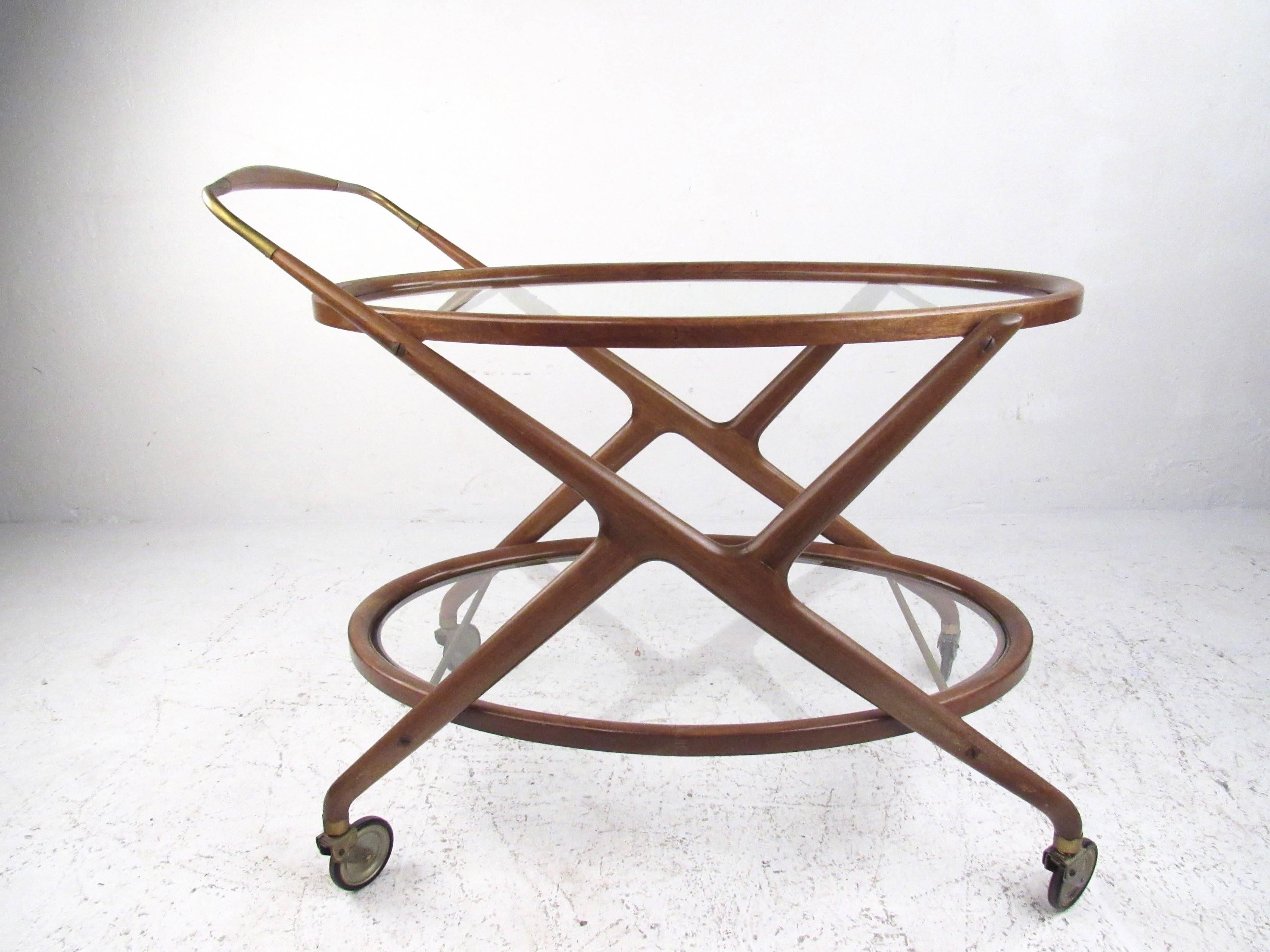 This sleek and stylish vintage Italian service cart features a beautiful combination of sculpted wood, brass trim, and glass trays. High quality Mid-Century construction is complimented by the elegant design of Cesare Lacca. Two-tier bar cart is
