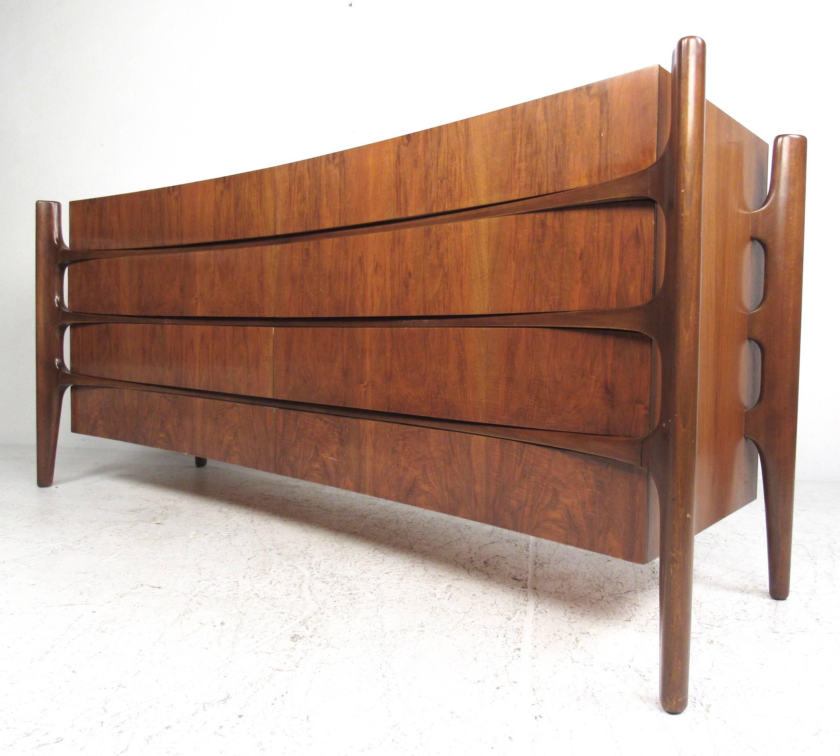 This four-piece Mid-Century bedroom set by William Hinn features an iconic concave sculpted design in a stunning vintage walnut finish. Unique two-piece highboy dresser, low eight-drawer dresser and nightstands are all from a matching set, having