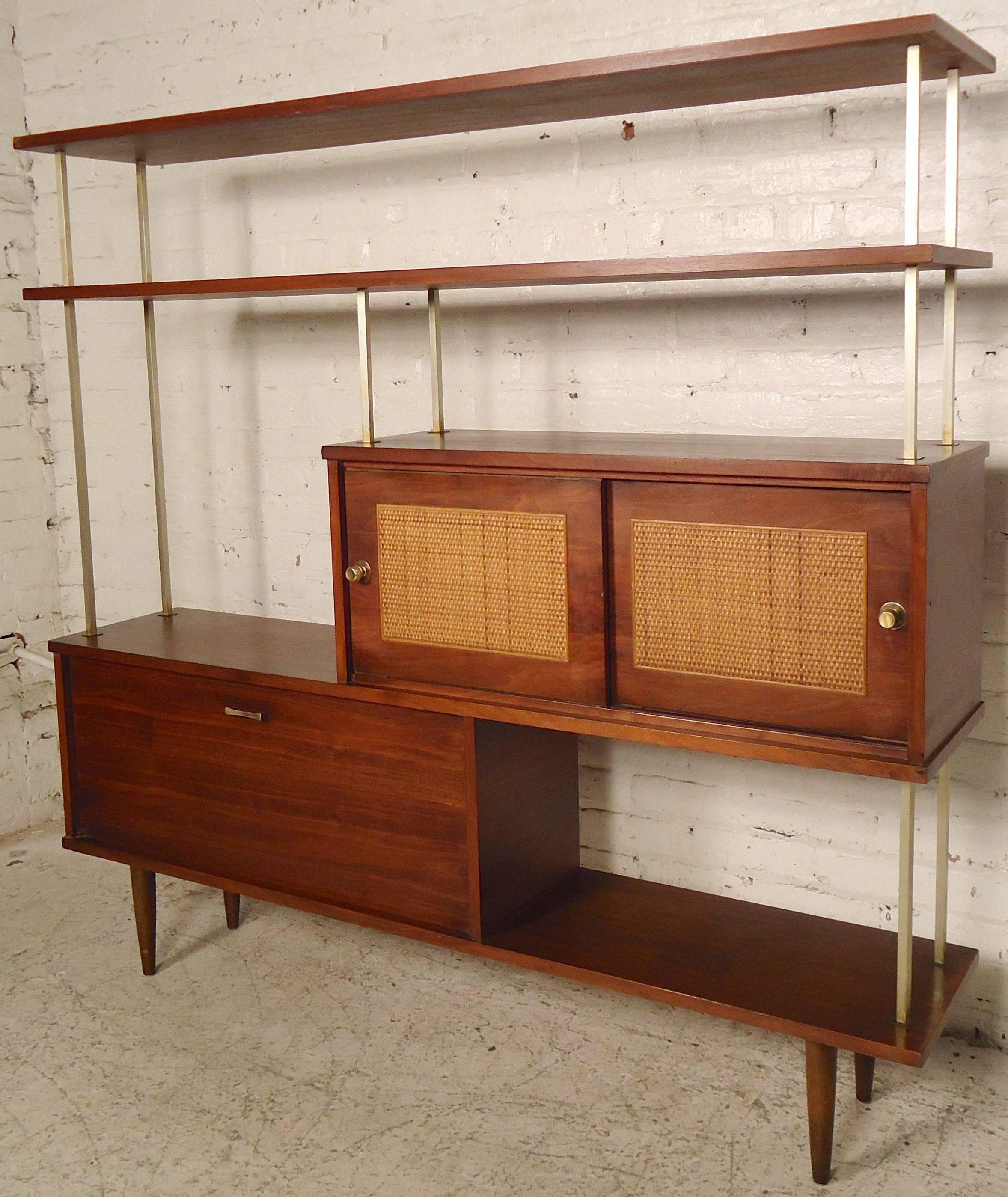 Beautiful walnut Mid-Century standing unit with mirrored cabinet, sliding cane front doors, and ample shelving. Handsome brass accenting frame and hardware, tapered legs and finished walnut grain.

(Please confirm item location - NY or NJ - with