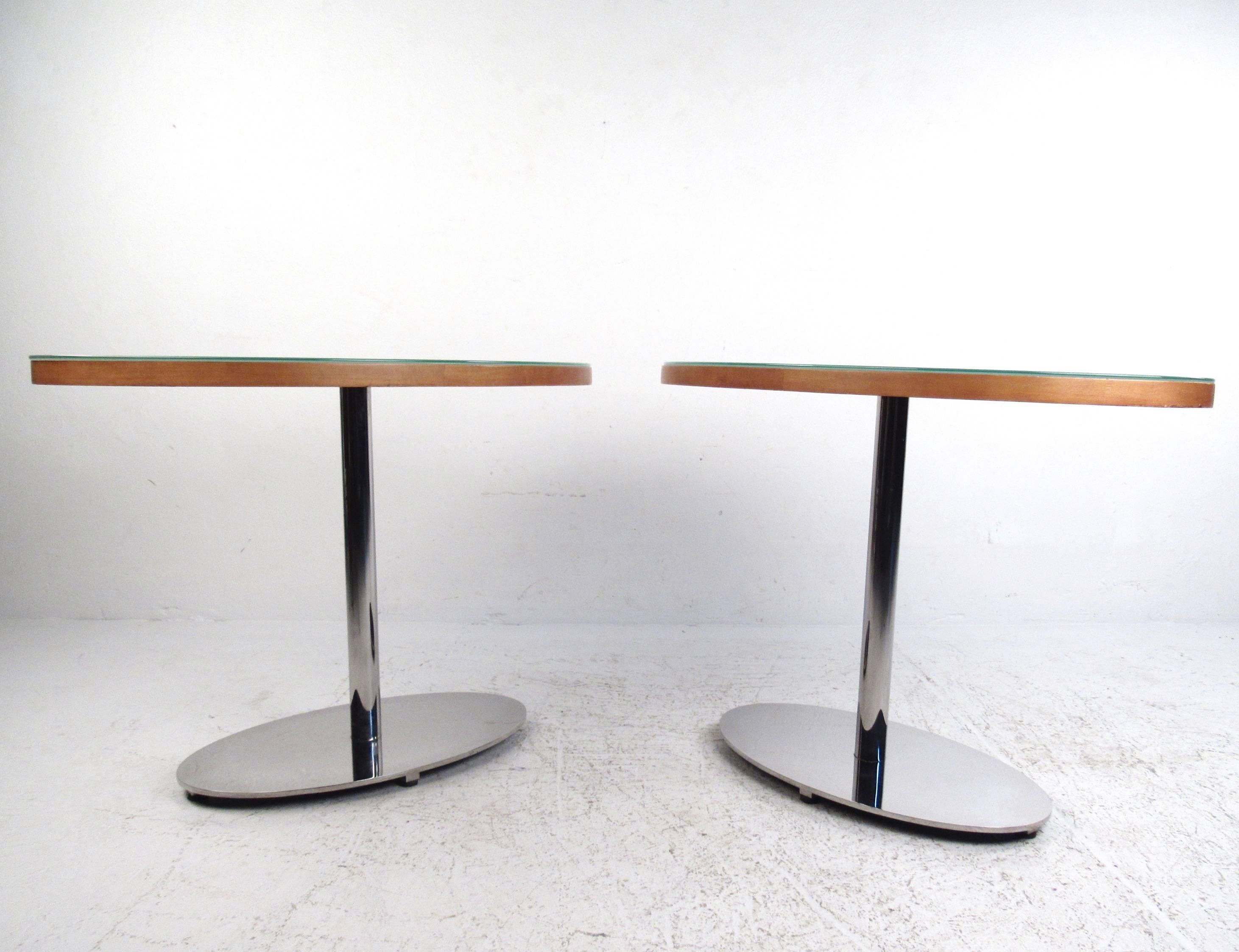 This contemporary modern pair of chrome base side tables make an excellent addition to a variety of interiors as side tables or for use as display tables. Oval wooden tops are protected with frosted glass, the modern style of the pair makes a unique