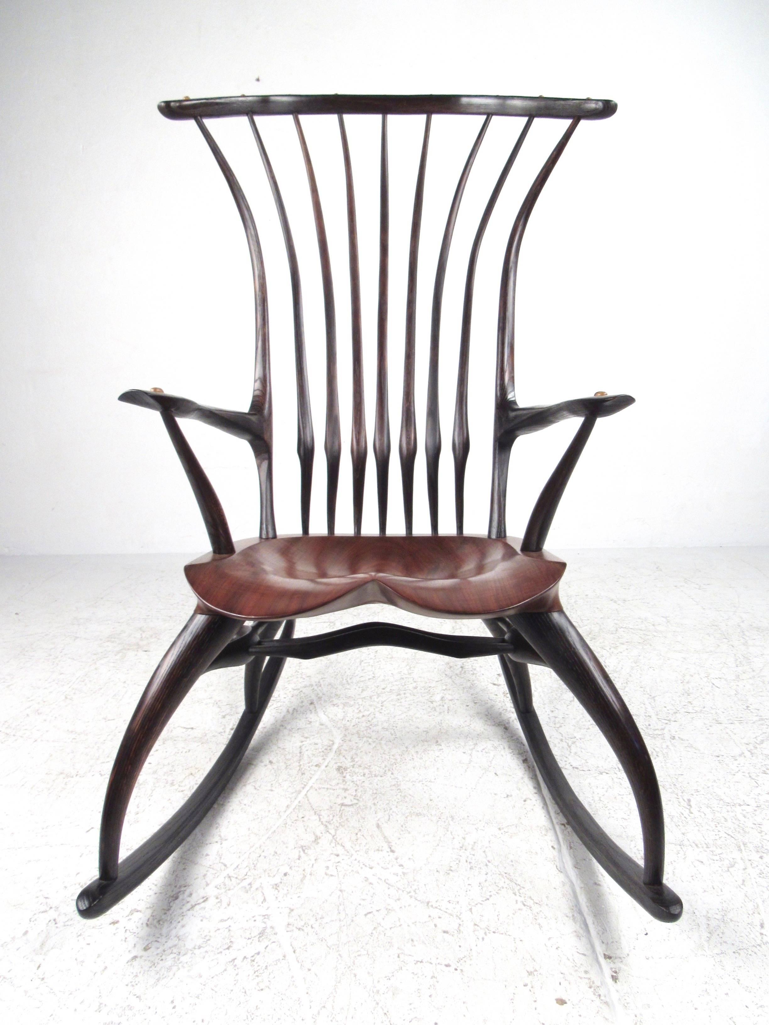 This stunning studio made rocking chair features beautiful sculpted hardwood frame with tapered spindle back, comfortably carved seat, and elegant sculpted rockers. This beautiful contemporary rocking chair makes an impressive addition to any