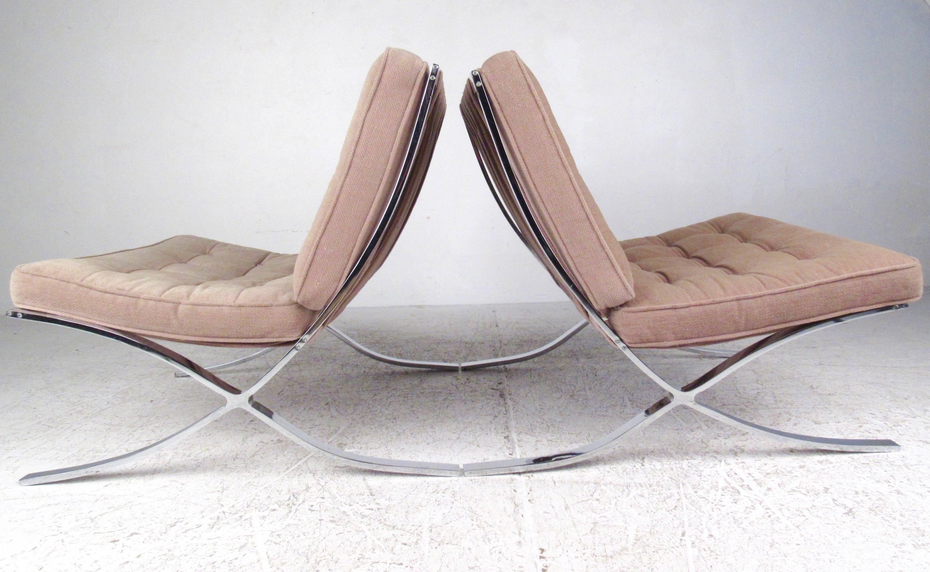 This vintage pair of chrome-plated lounge chairs feature the Mid-Century Barcelona style of Ludwig Mies van der Rohe. The curved metal frames and fabric strap backs showcase the distinctive modern design of the Mid-Century designer, providing a