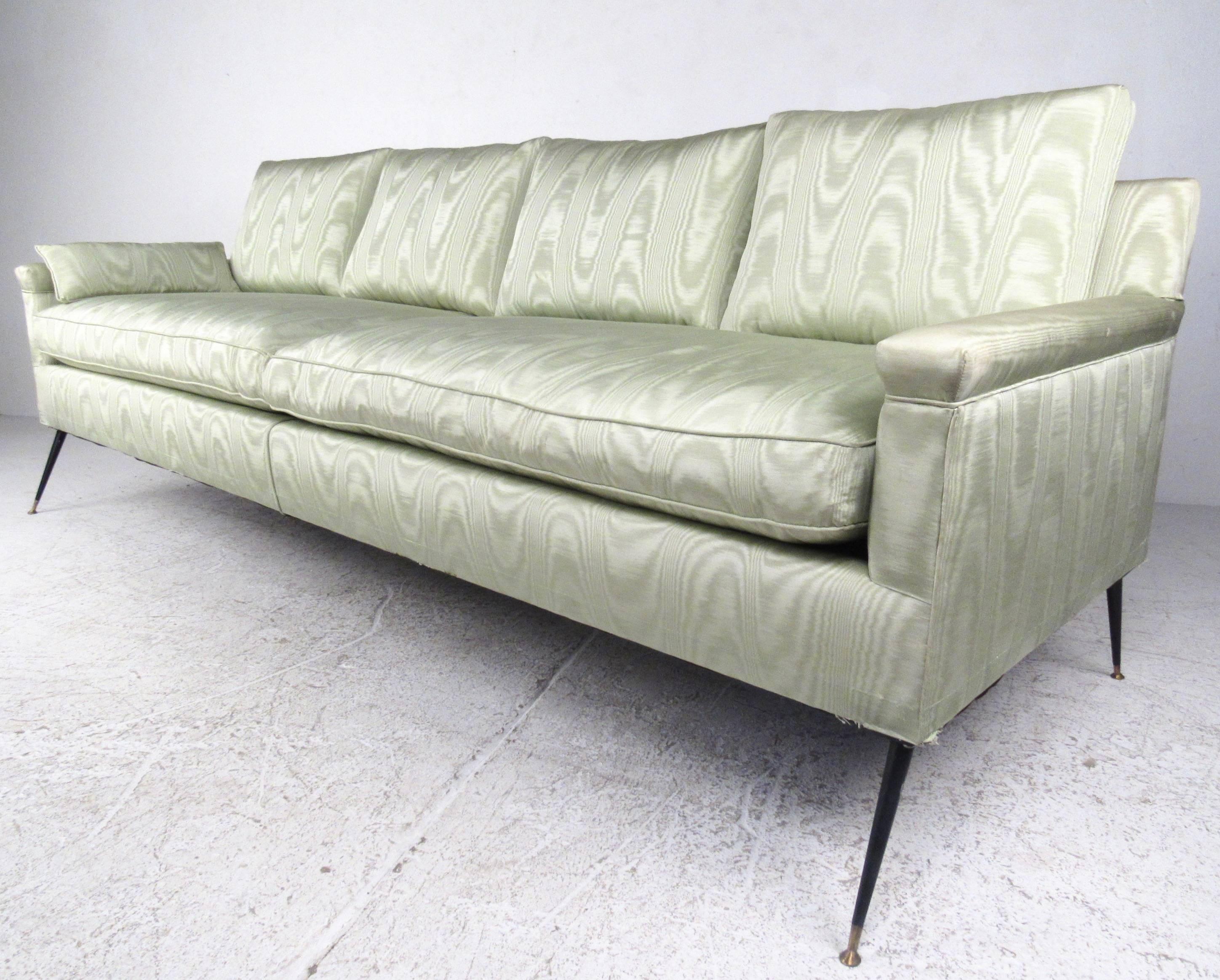 This four seat midcentury sofa features comfortable two cushion design complete with unique vintage fabric. Slender Italian style legs give the sofa a unique profile, while the wide and well stuffed seating makes this a comfortable addition to any