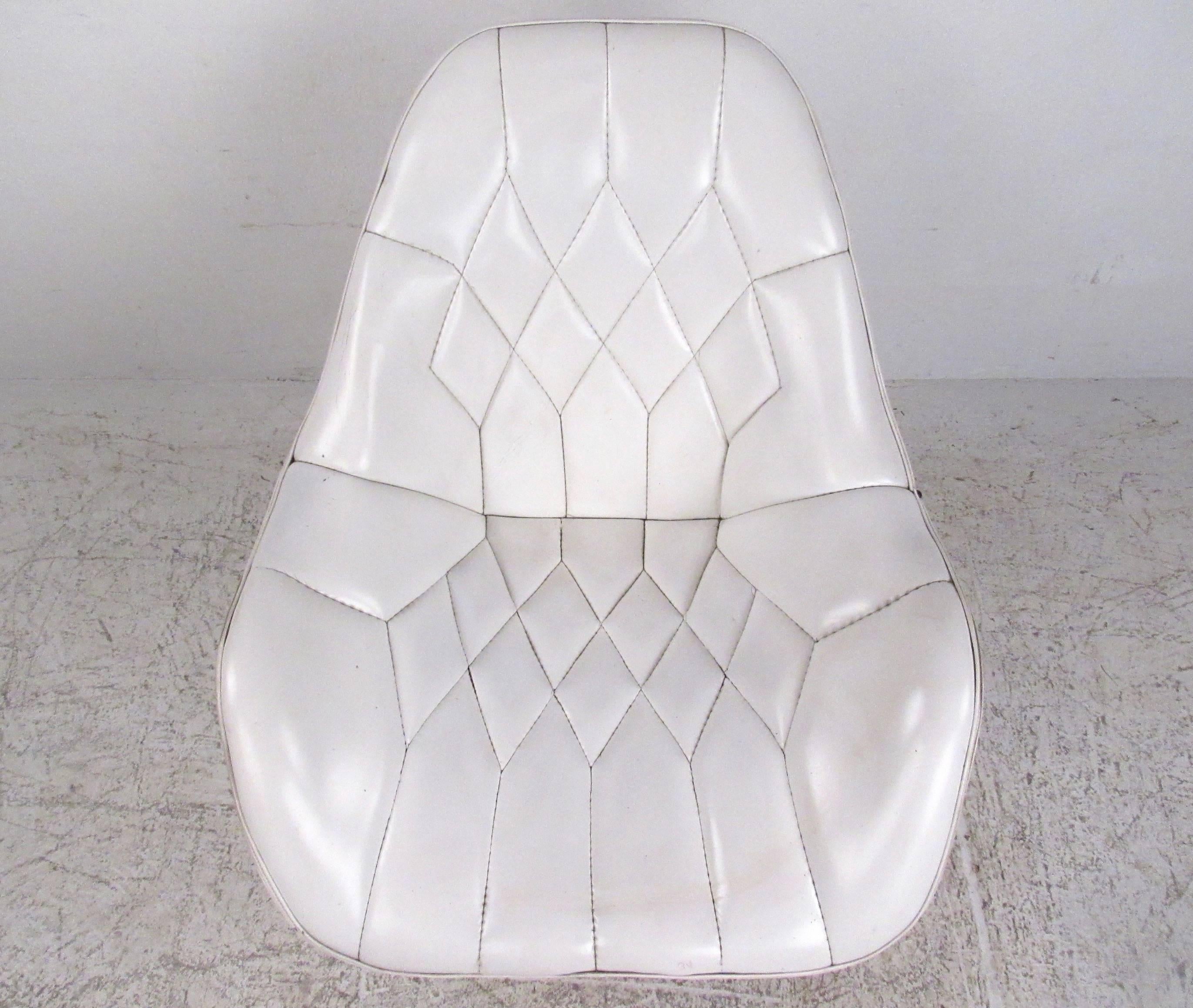 Ce fauteuil de salon pivotant de style Mid-Century présente une assise en vinyle ornée de surpiqûres et un confortable dossier sculpté. La base métallique noire unique avec garniture en aluminium ajoute au style vintage unique de ce fauteuil