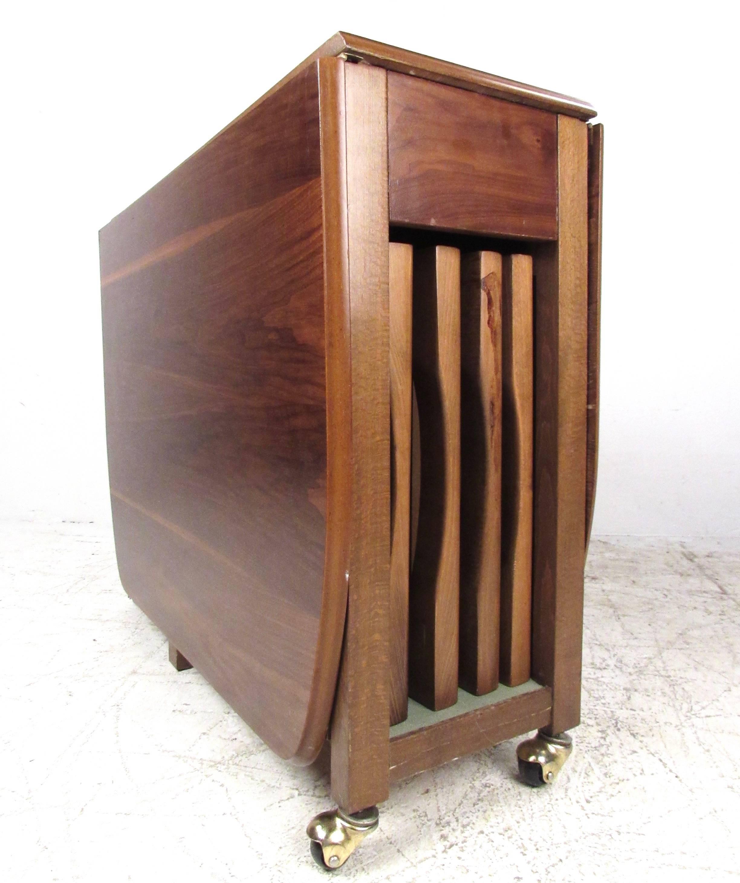 This vintage modern drop-leaf table makes a convenient and versatile addition to any interior, providing a mix of versatile table space and storage for the matching set of folding chairs. Comfortable vinyl upholstery add to the mid-century charm of