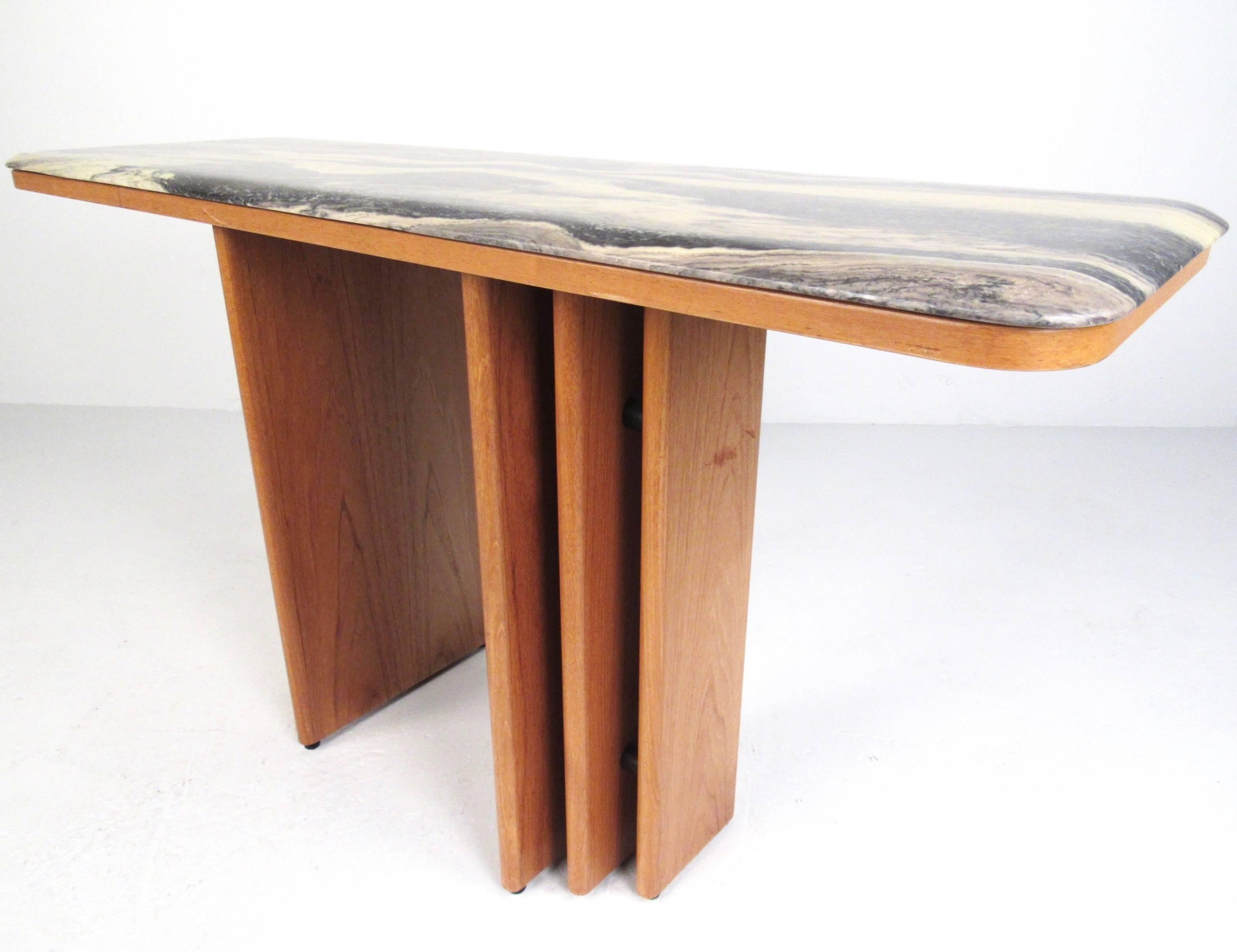 This vintage Danish teak console table features a sleek and stylish flared base design topped with a stunning marble top. Rounded edges and the unique Mid-Century Modern style of this Scandinavian console table make it a beautiful addition to