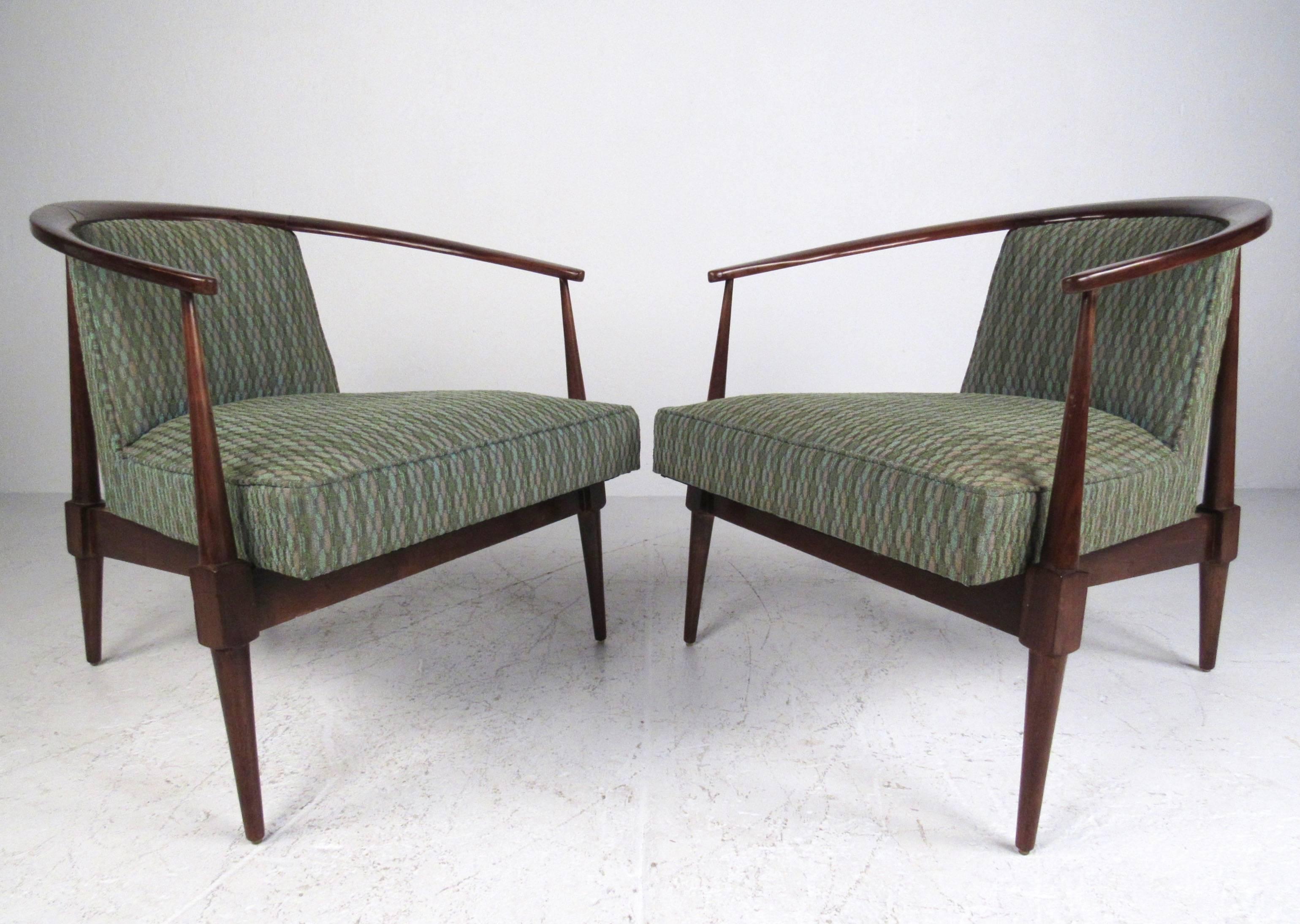 This elegant pair of Mid-Century armchairs features slender sculpted wood frames with curved backs and spacious upholstered seats. The stylish design of the pair combines high quality vintage design with timeless comfort. Please confirm item