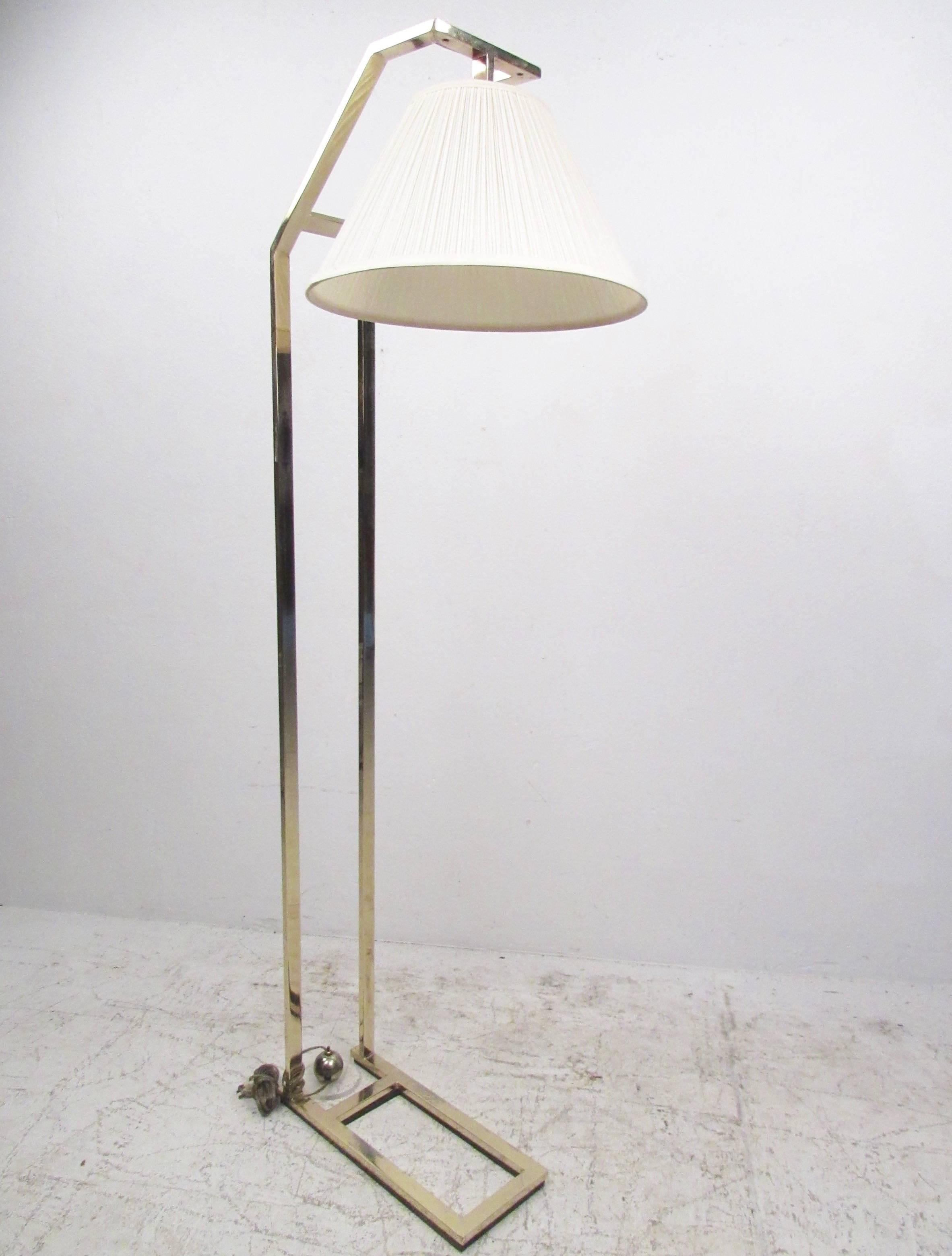 This contemporary modern cantilever style floor lamp features simplistic yet elegant design, with a stylish bend making it an ideal reading lamp for any modernistic seating area. Brass finish and wide fabric shade add to the appeal of this unique