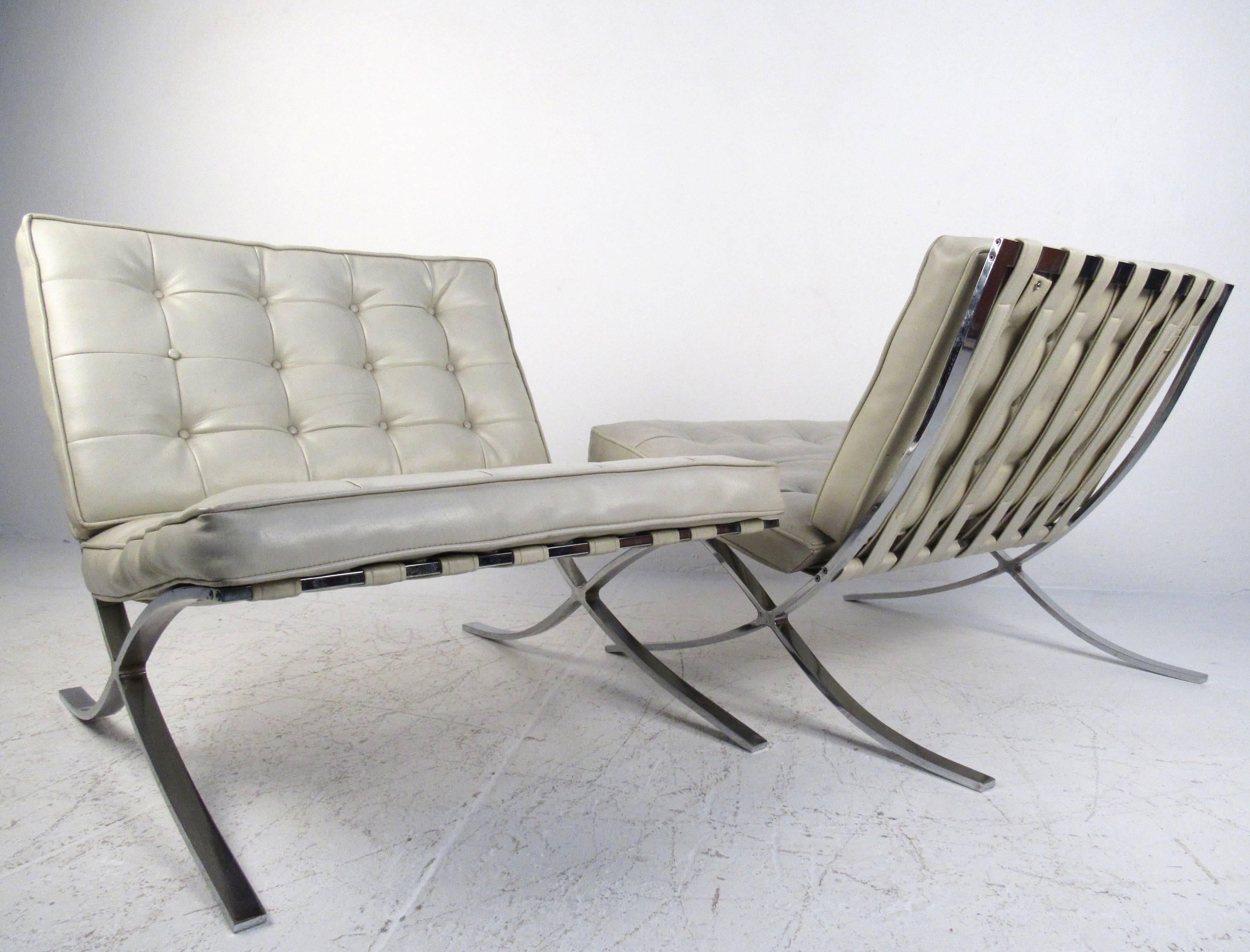 This pair of vintage lounge chairs features wide tufted vinyl seats, strap seat webbing and sleek/stylish chrome frames. This stylish mid-century pair is inspired by the iconic style of Mies van der Rohe and make a comfortable addition to any