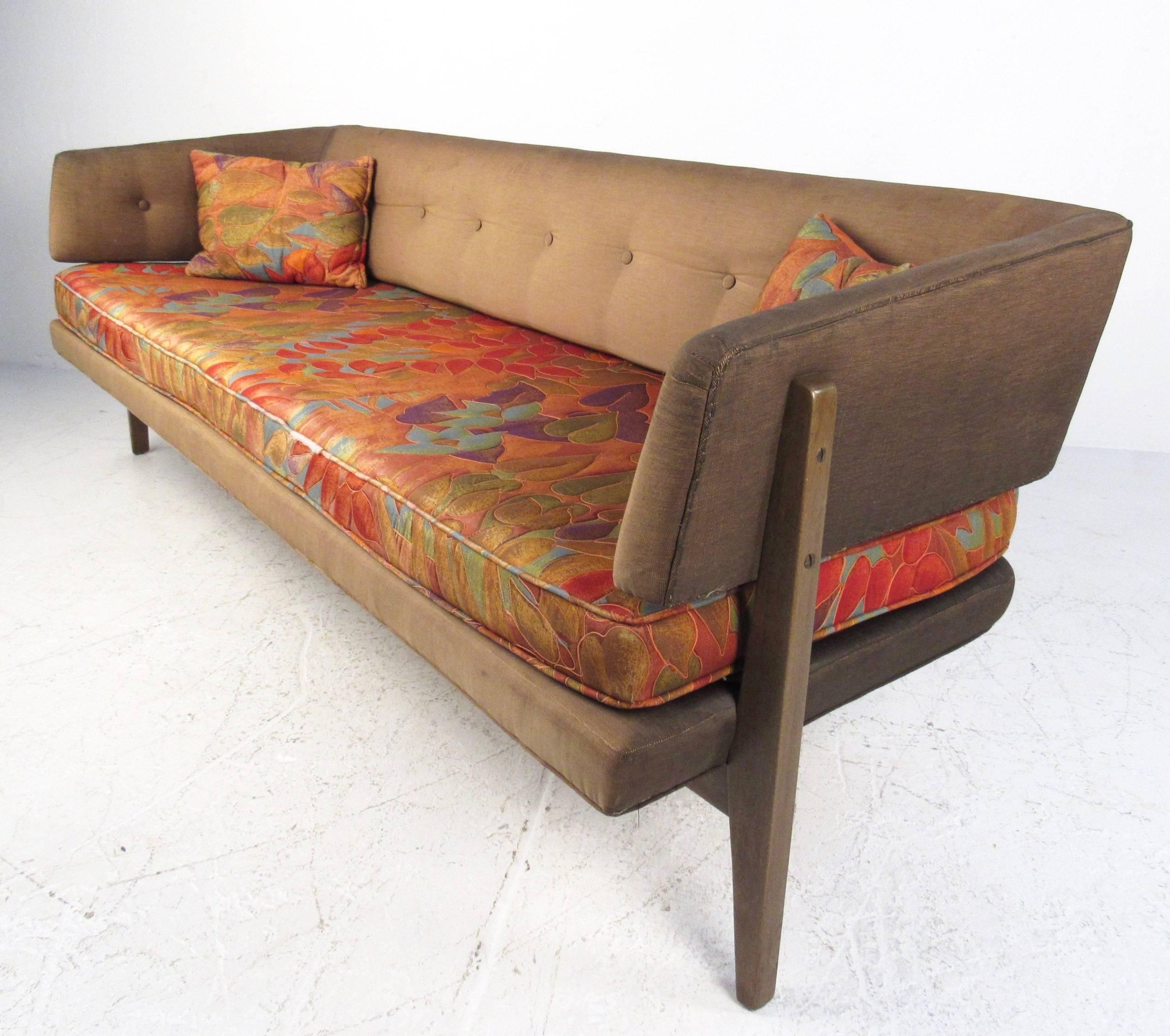 This stunning vintage sofa by Edward Wormley for Dunbar features a tufted sculptural seat back with unique tapered walnut legs. Uniquely covered vintage throw pillows match the two tone upholstery of the sofa, whose modern lines and comfortable