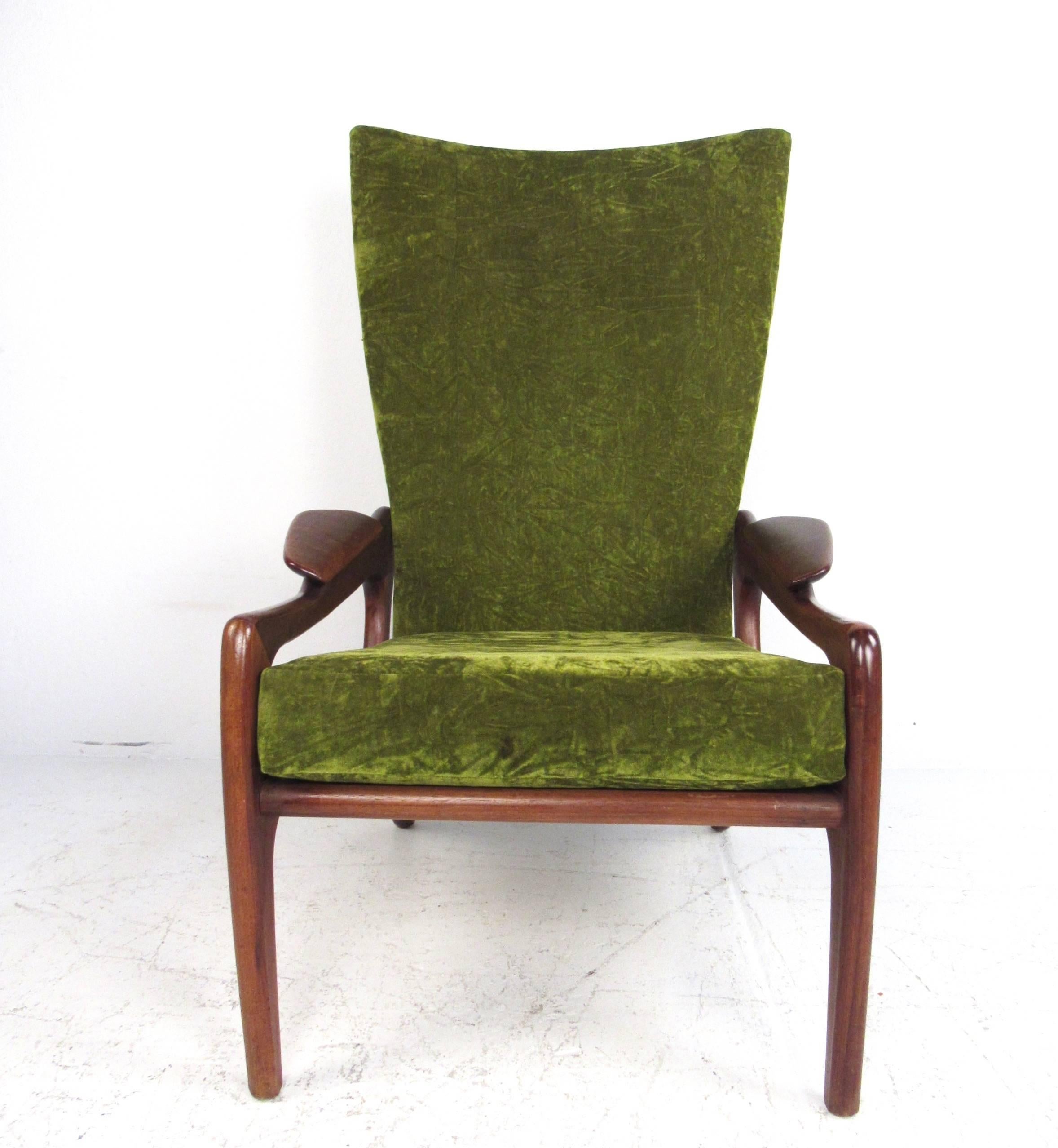 This unique high back lounge chair features sculptural walnut frame with an impressive wingback design. Rubber strap seating with a plush cushion in velvet like upholstery make this chair as comfortable as it is stylish. This Mid-Century armchair by