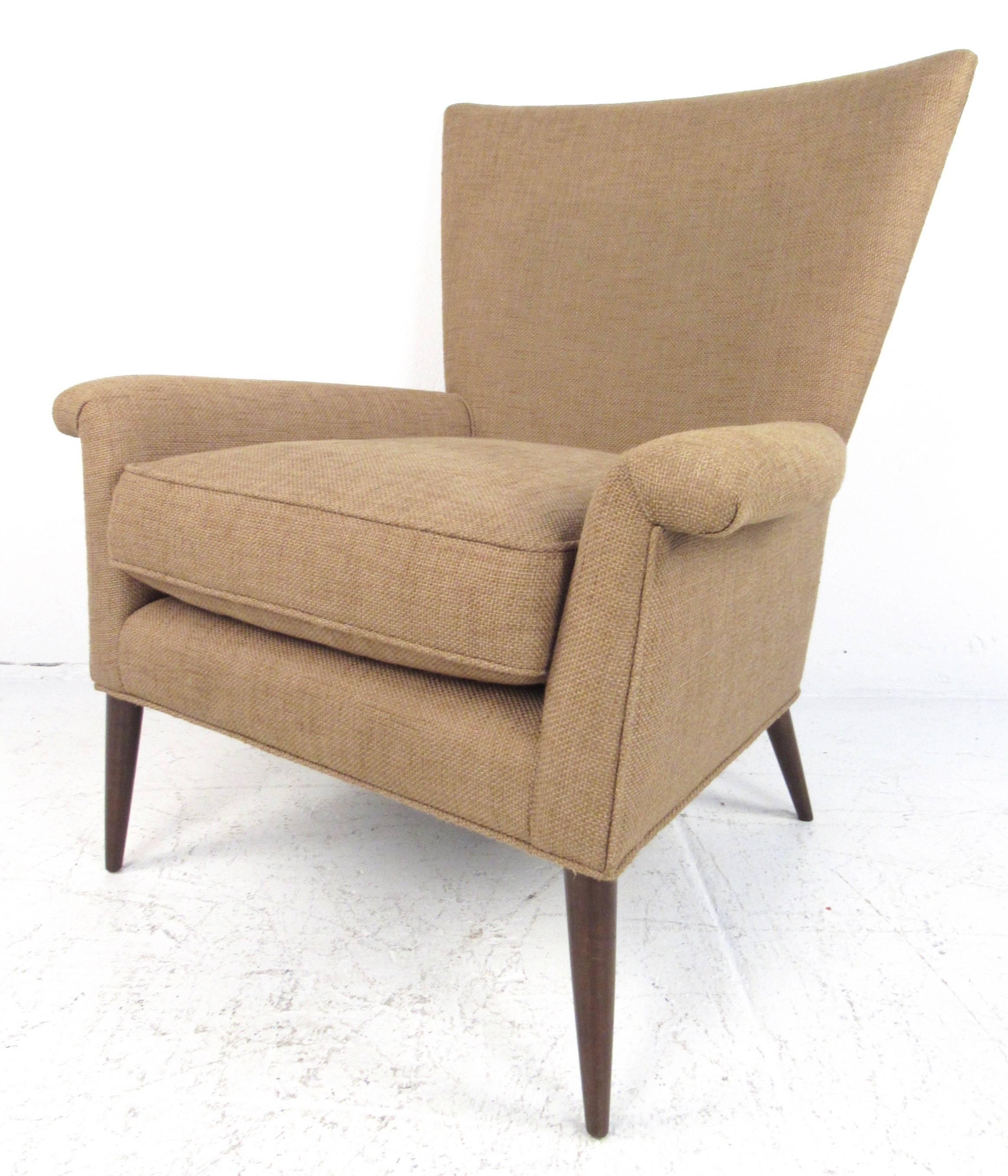 This vintage modern wingback lounge chair boasts an elegant high back design with slender tapered legs and plush upholstered seating. Optional back pillow and sculpted armrests enhance optimal comfort. Please confirm item location (NY or NJ).