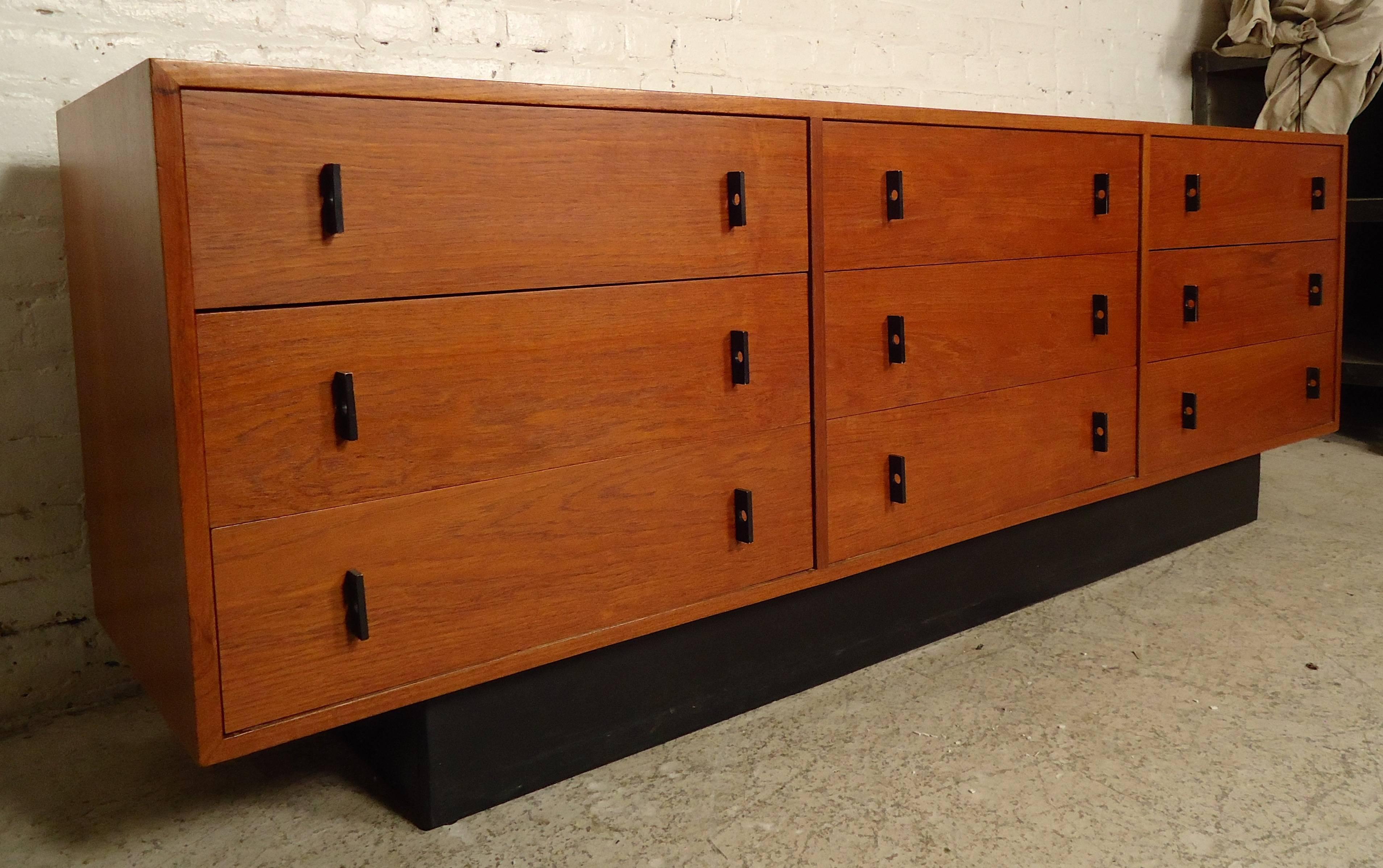 Unique vintage-modern dresser features nine spacious drawers, black metal pulls, and a black base. Warm teak grain throughout.

Please confirm item location (NY or NJ).