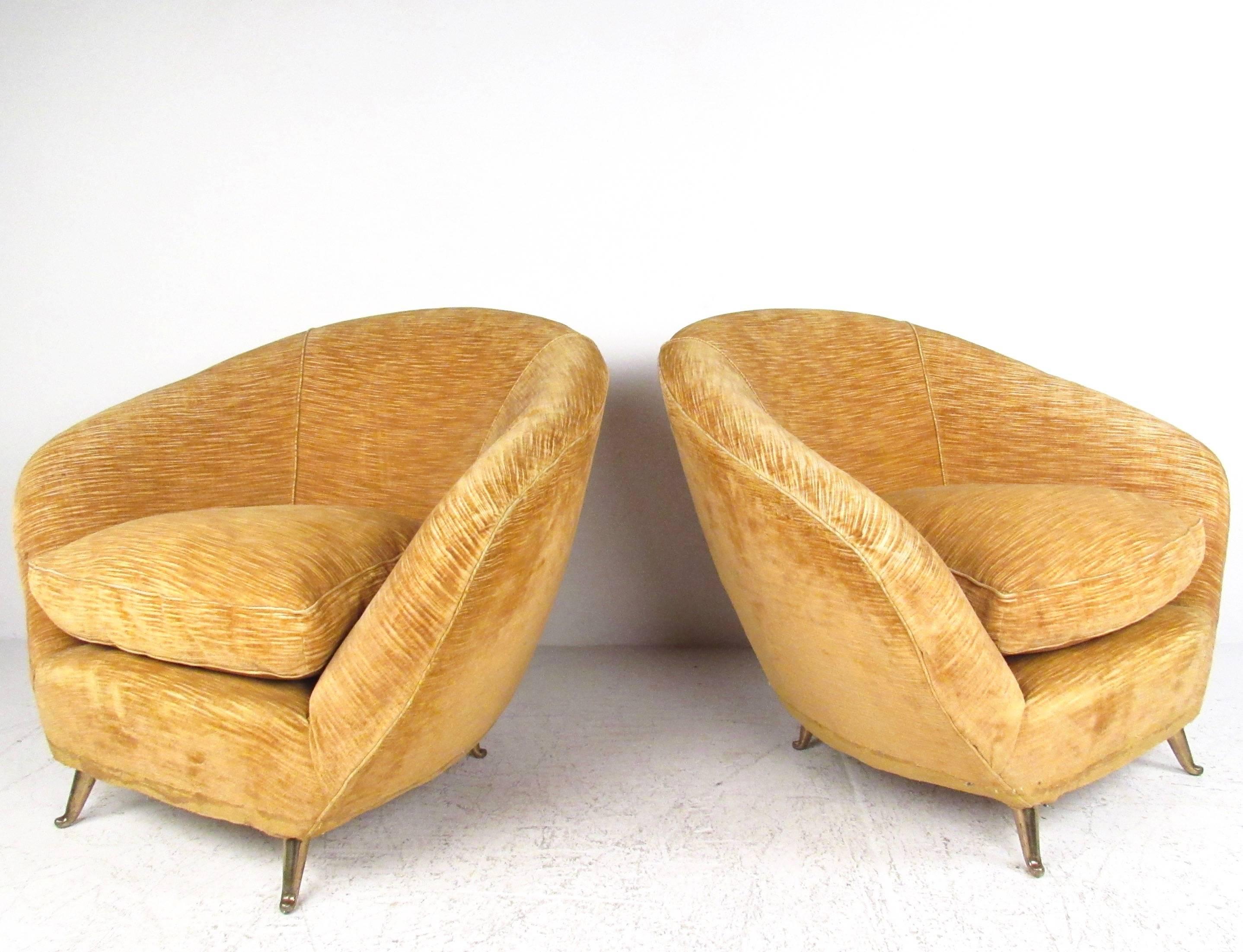 This unique pair of stylish sculptural lounge chairs feature Mid-Century Italian design in plush velvet upholstery. Angled brass legs, plush and well-padded upholstery, and comfortable rounded seat backs make this vintage pair of lounge chairs the