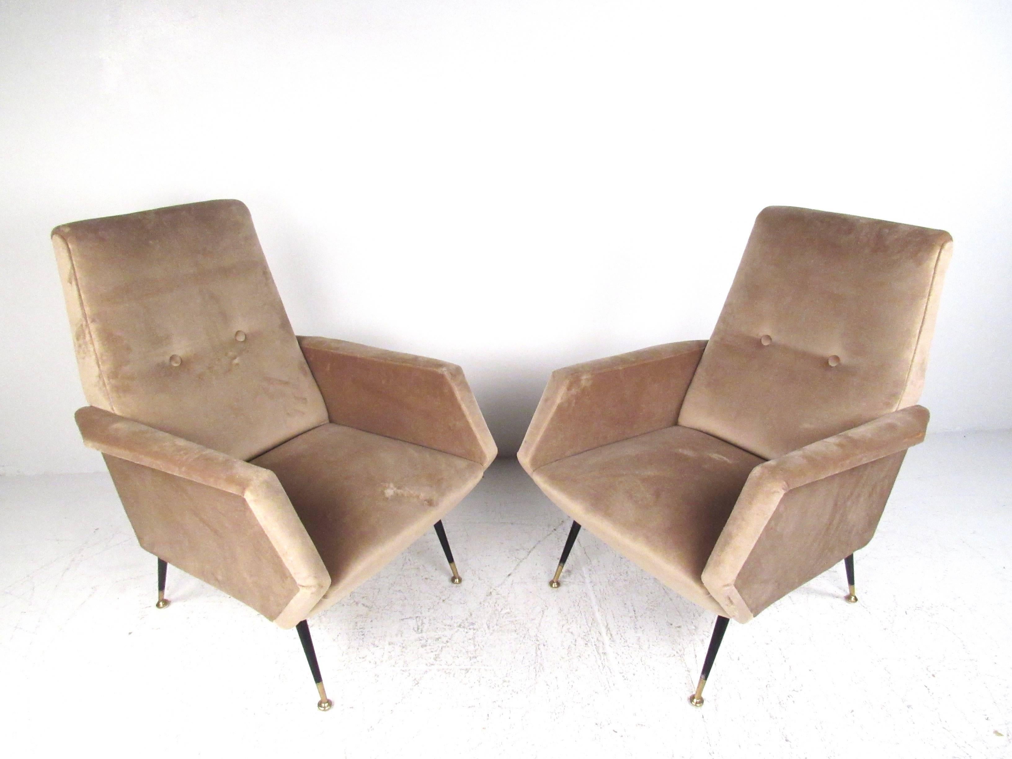 This beautiful pair of upholstered lounge chairs features plush upholstered fabric with tufted details, tapered brass tipped metal legs, and comfortable seating proportions. This matching Mid-Century pair looks great from any angle, with sculpted