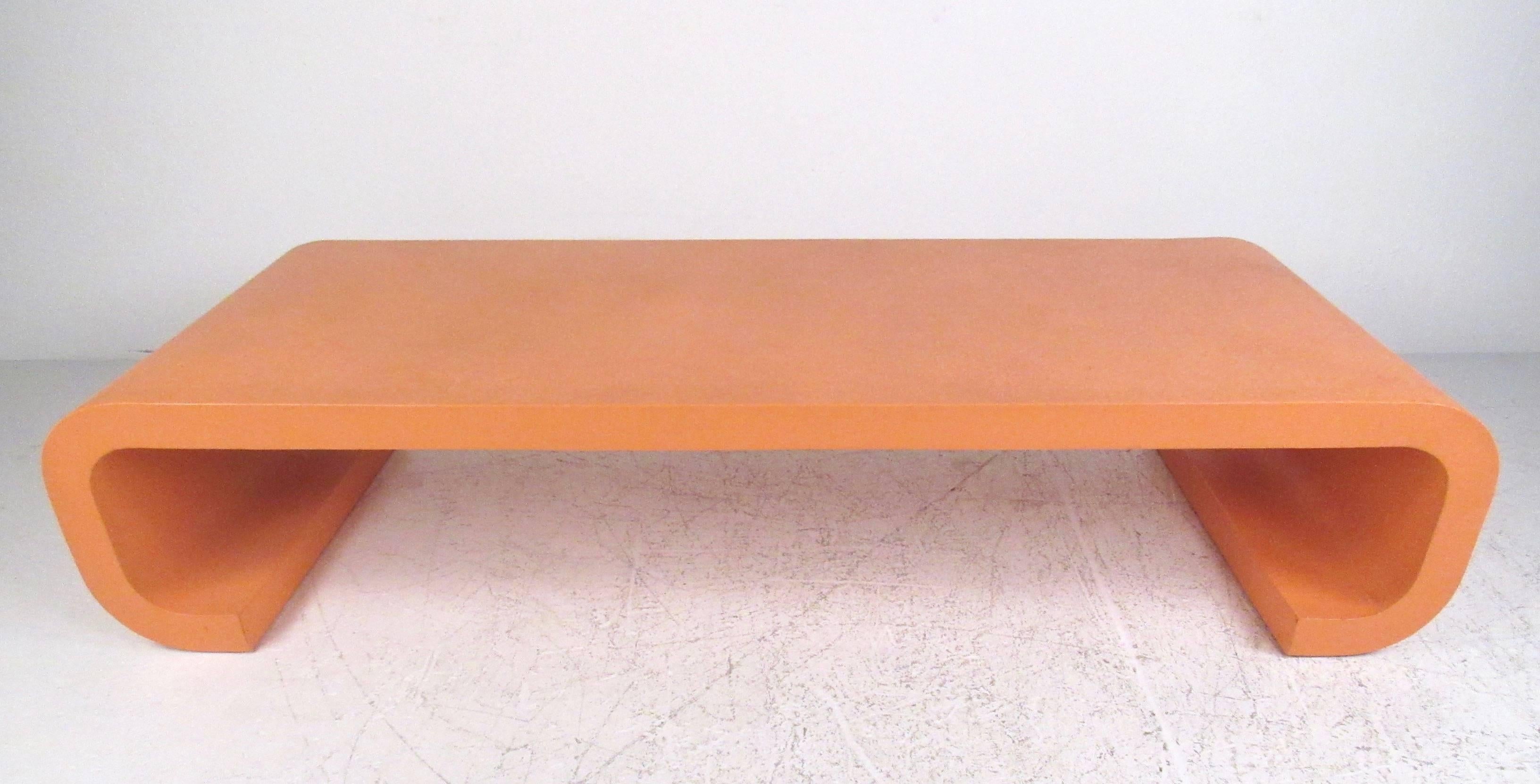 This large grass-cloth finish coffee table has a unique orange/pink paint color, with Karl Springer style scrolled legs. Its impressive color, shape, and size make this Mid-Century coffee table the perfect piece for home or office. Please confirm