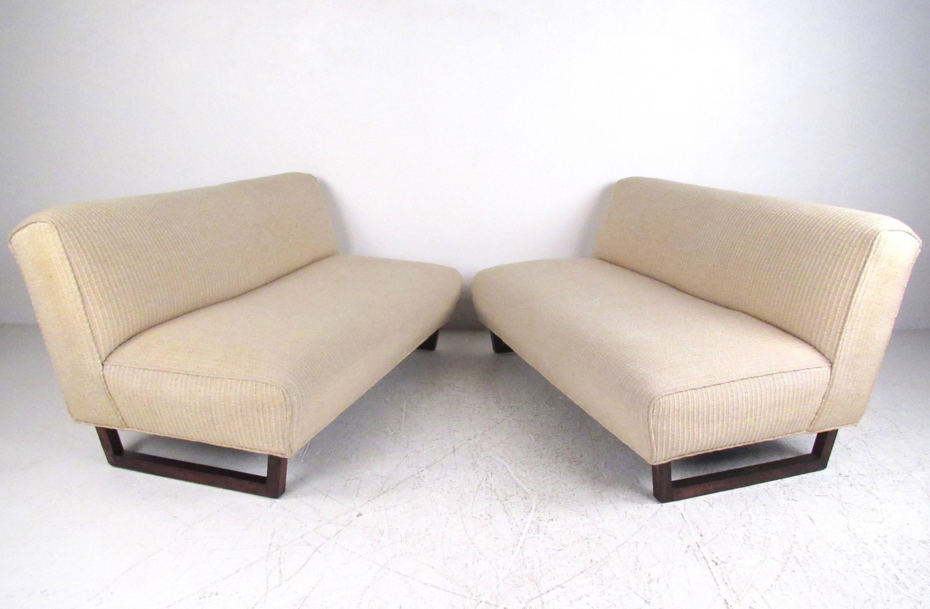 This vintage pair of armless sofas feature unique rosewood sled legs with stripped vintage fabric. Comfortable low seating for any interior, these low profile settees make a stylish seating addition to home or business. Please confirm item location