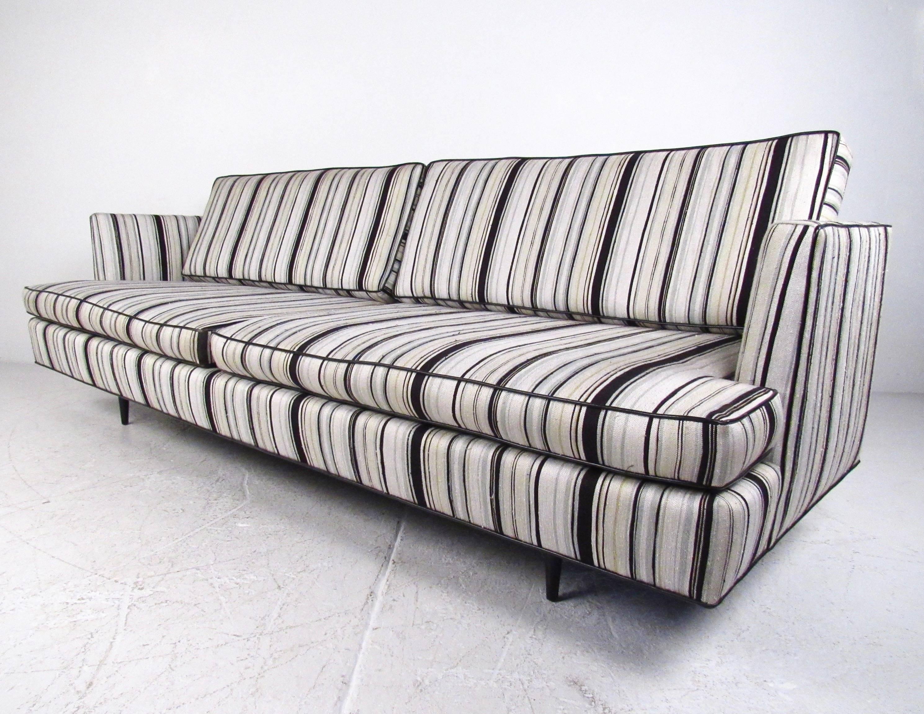 This spacious Dunbar sofa features deep upholstered seats with unique vintage striped fabric. The cutaway armrests and well-proportioned design add to the Mid-Century appeal of this large sofa, making it an impressive addition to any seating area.