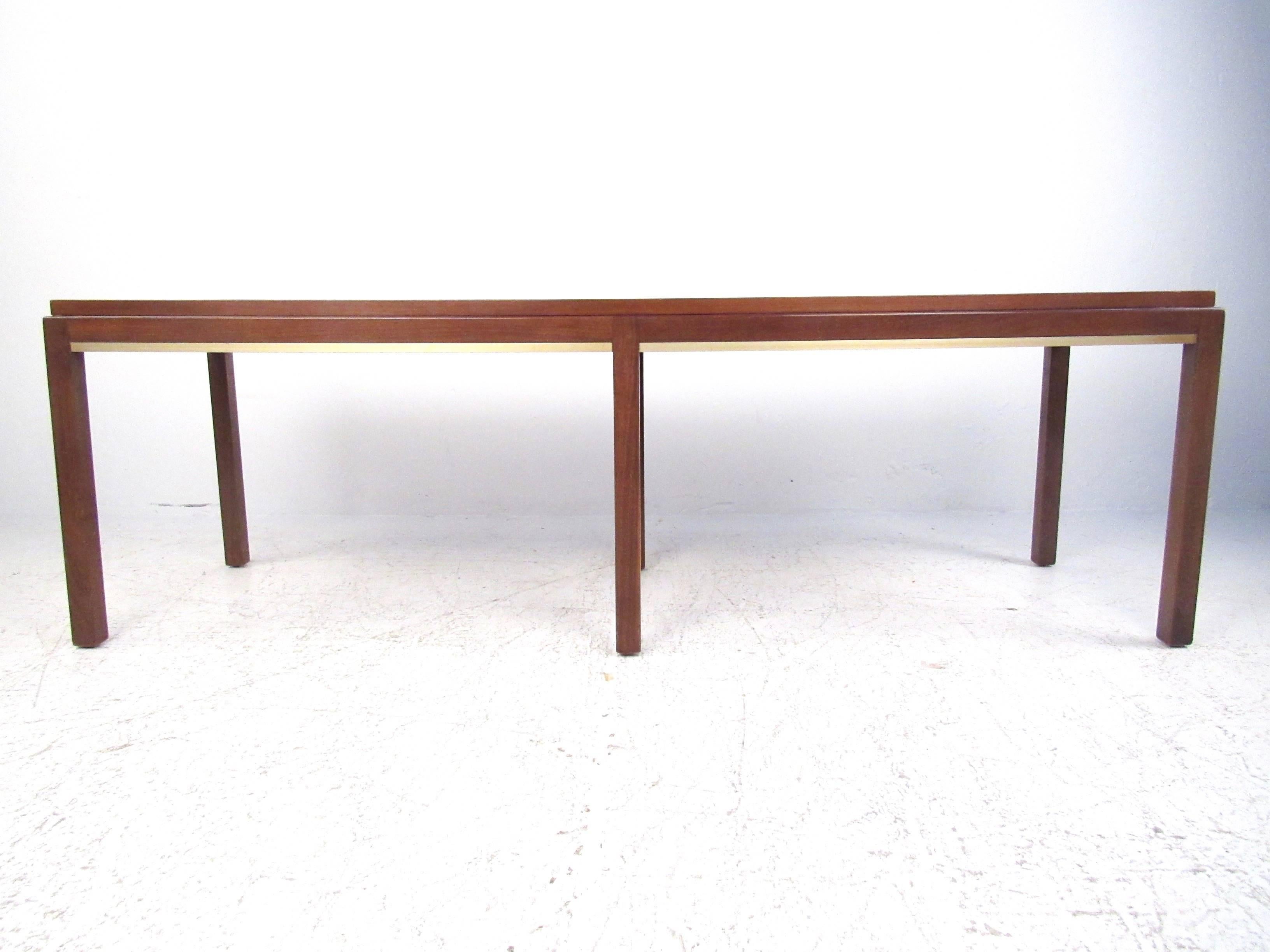 This vintage modern rectangular coffee table features statuesque walnut construction and elegant brass trim. This uniquely tall table features six slender legs for the perfect mix of support and style. Please confirm item location (NY or NJ).