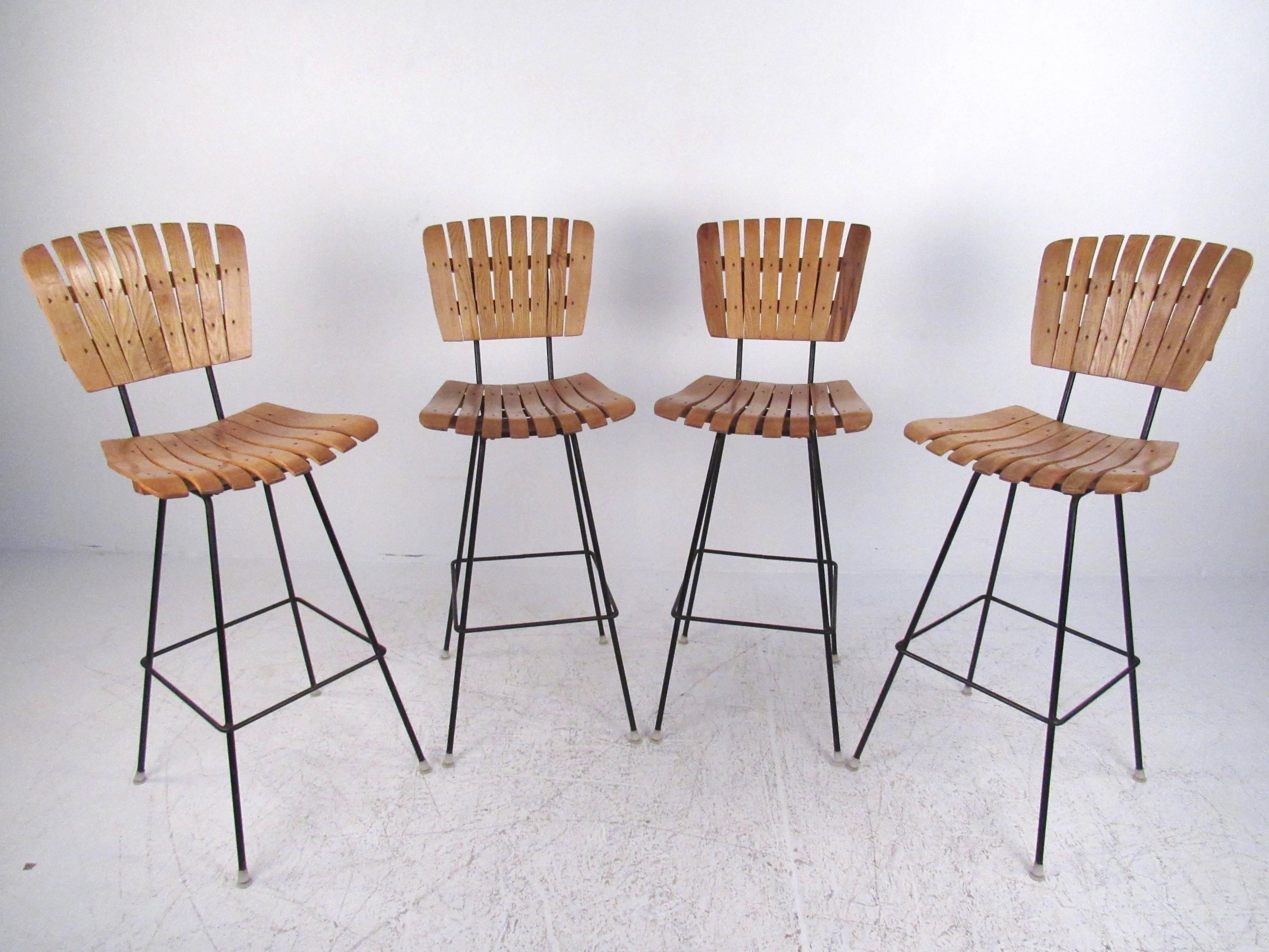 This set of four mid-century slat stools feature iron legs and unique oak slats. Shapely bar stools make a unique vintage addition to any bar or counter. Please confirm item location (NY or NJ).