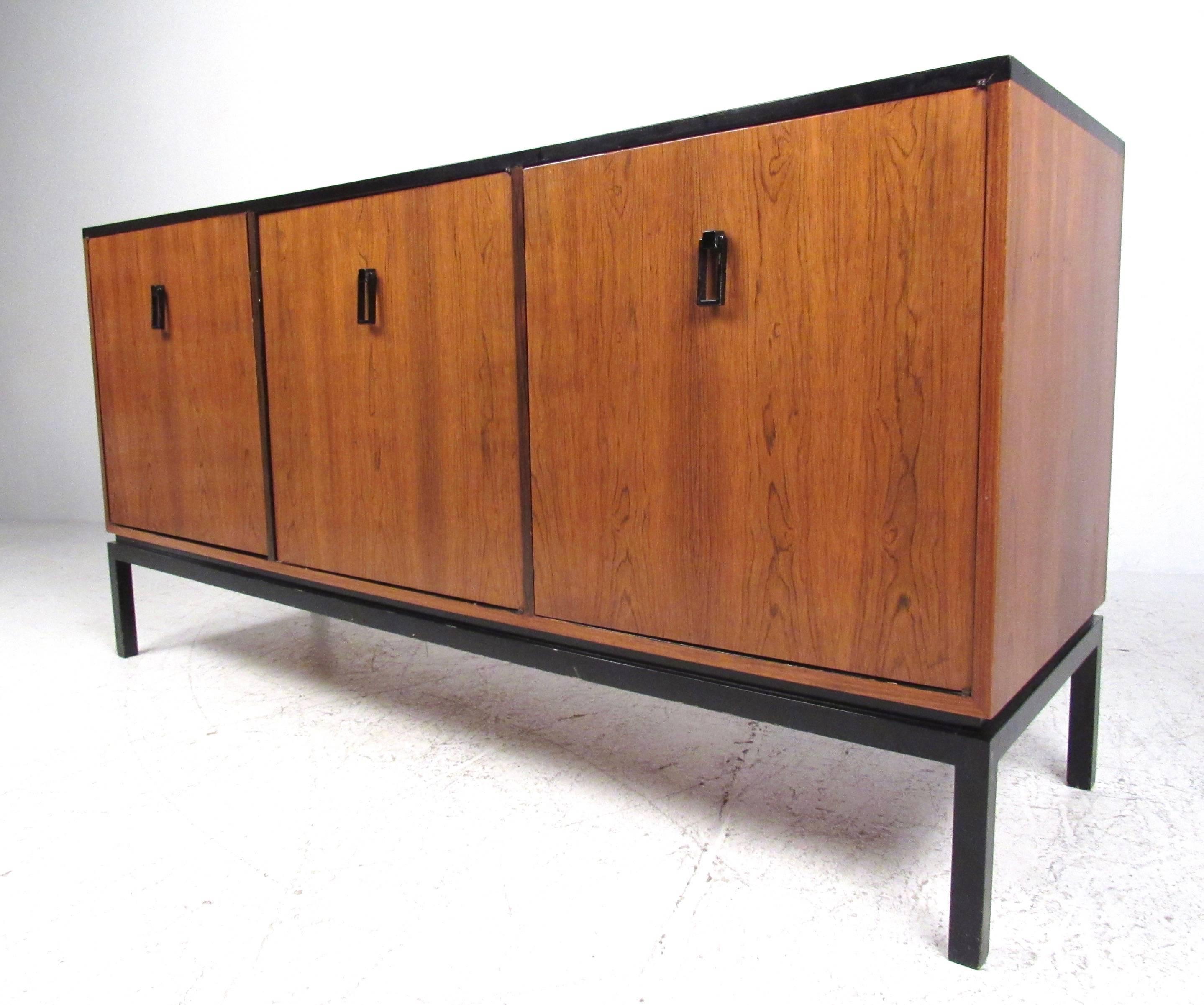 This vintage modern Dunbar credenza features a lacquered hard wood base, spacious interior cabinets, and unique metal pulls. This beautiful Mid-Century piece is perfect for use as a television console, dining room sideboard, or for occasional office