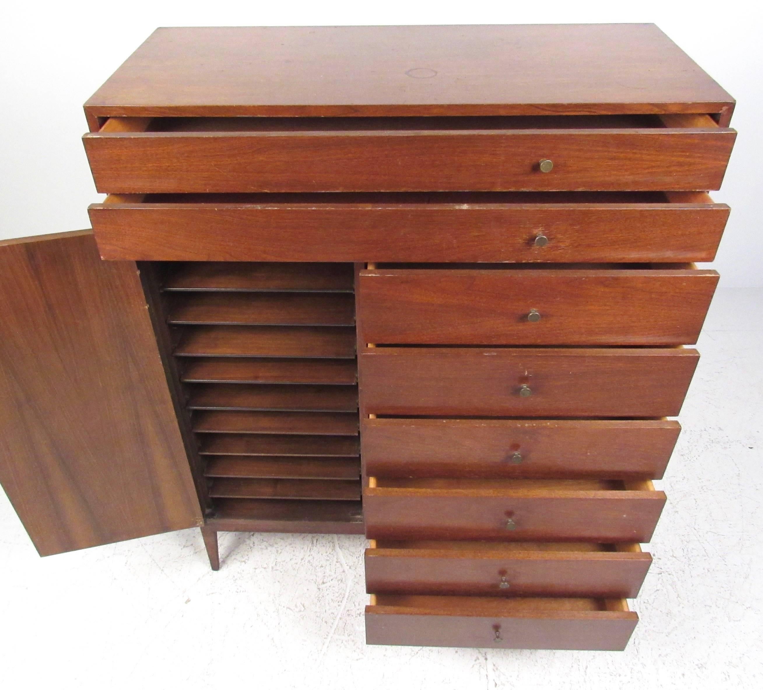 This stunning highboy dresser features unique graduated drawers with an addition cabinet containing easy slide shelves for ease of access. The unique design details on this mid-century dresser make this Paul McCobb style storage dresser a stylish